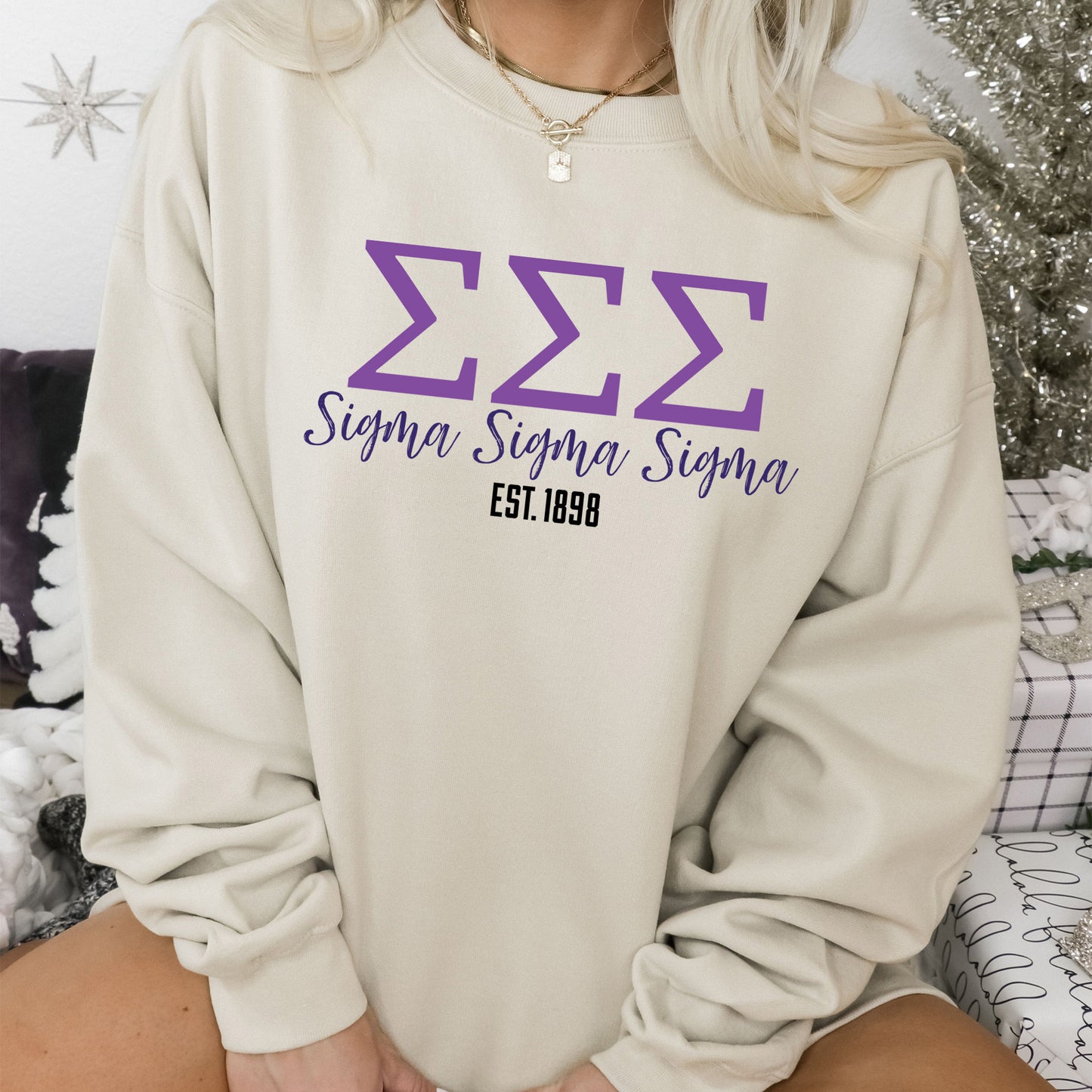 a woman sitting on a bed wearing a sweatshirt