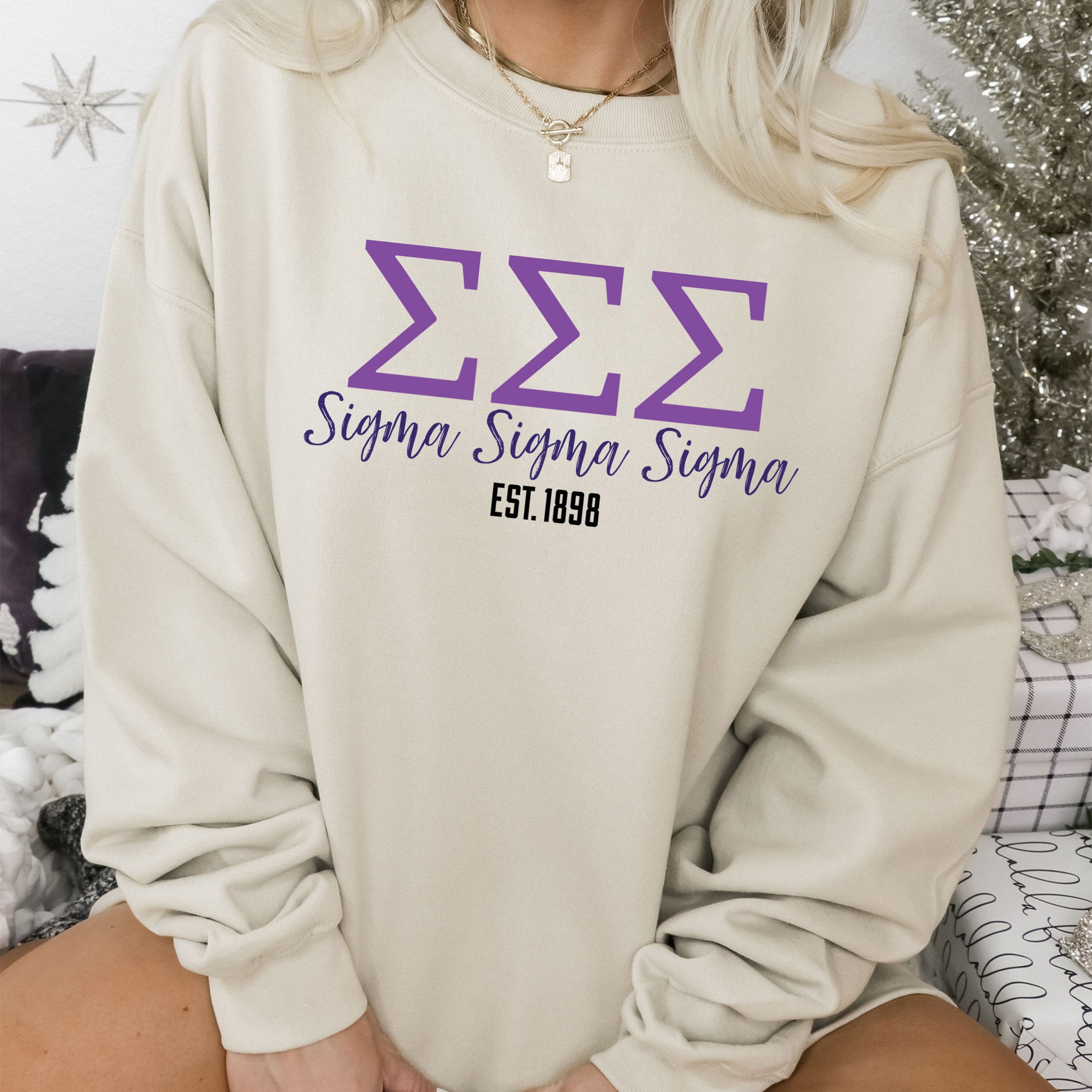 a woman sitting on a bed wearing a sweatshirt
