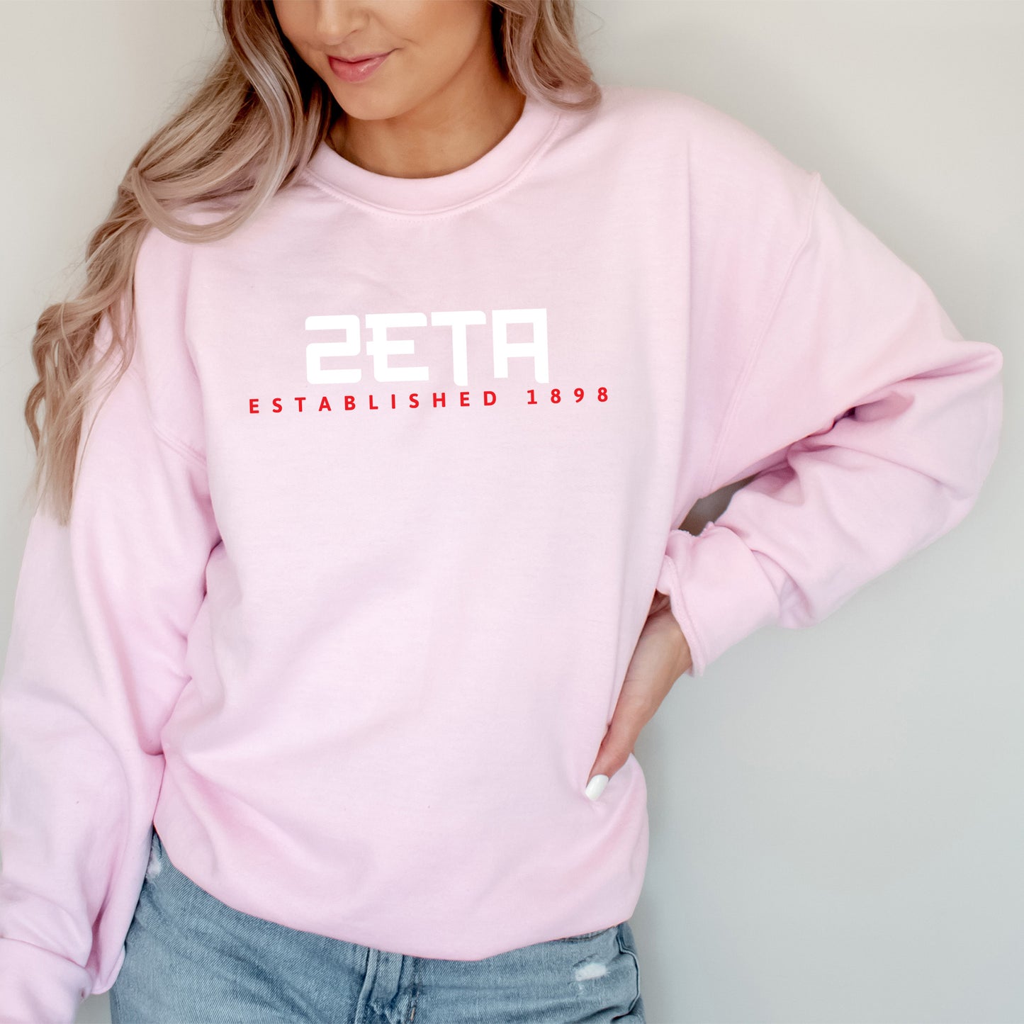 a woman wearing a pink sweatshirt and jeans