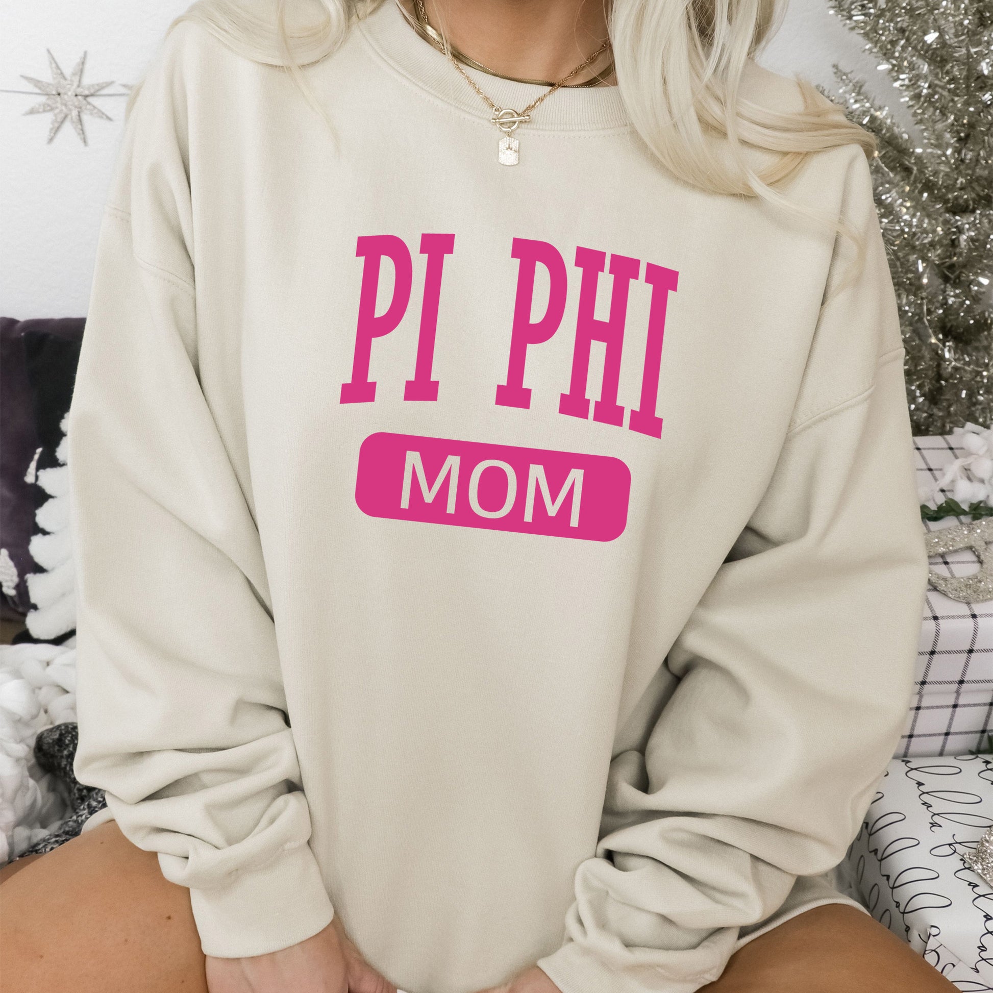 a woman wearing a sweatshirt that says pi phi mom