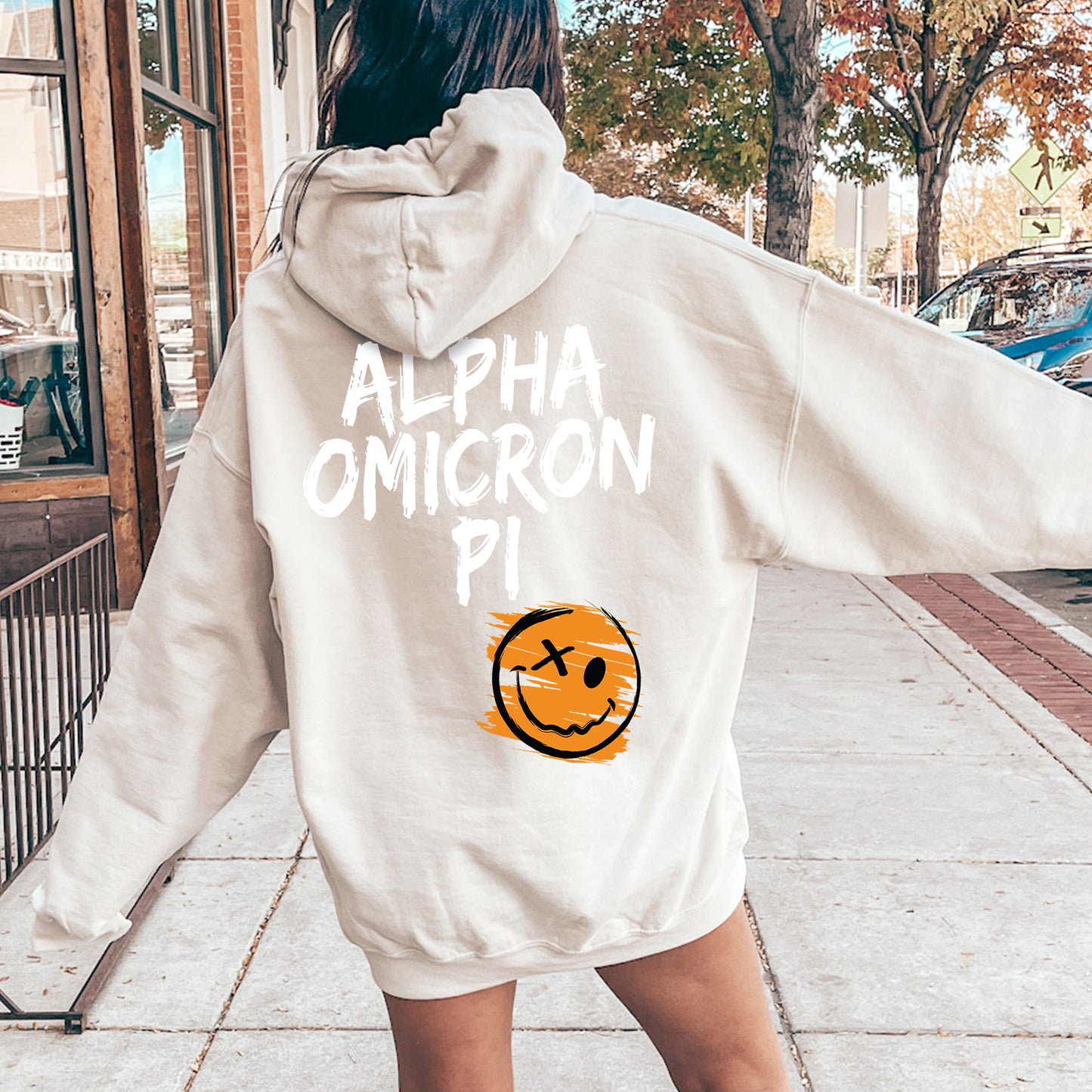 a woman walking down a sidewalk wearing a white hoodie