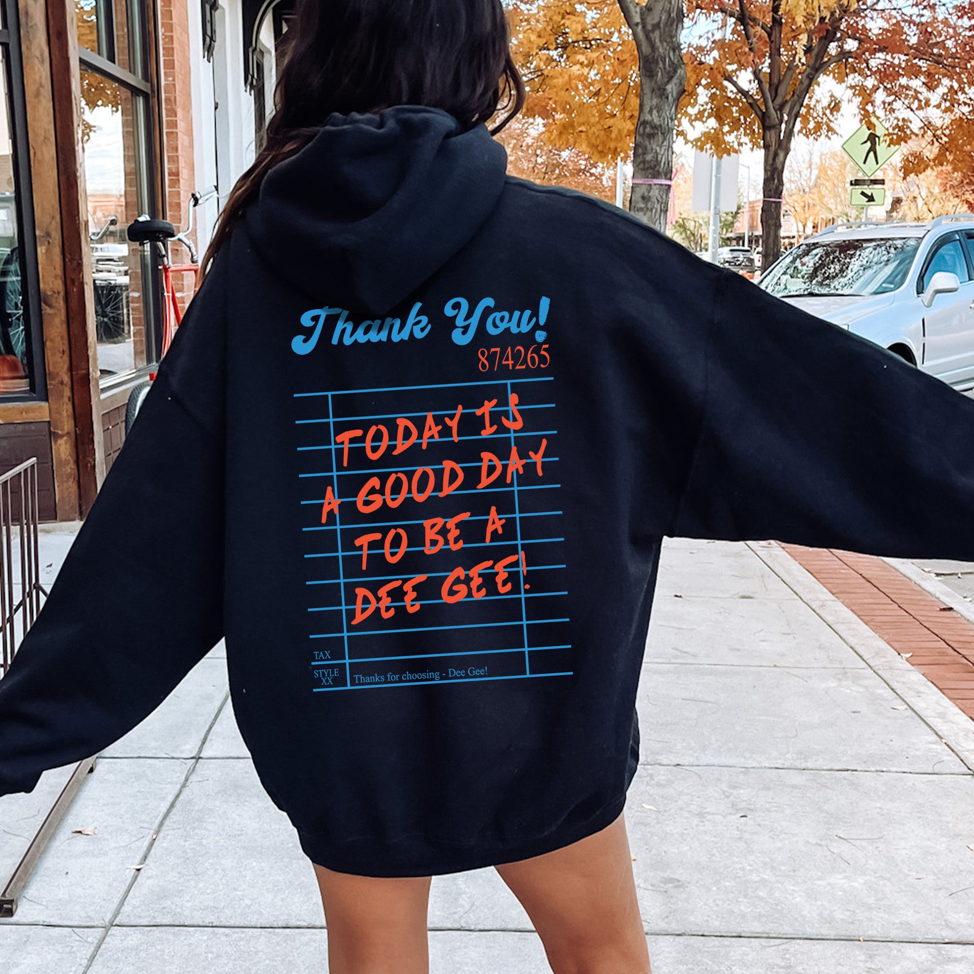 a woman in a black hoodie is walking down the street