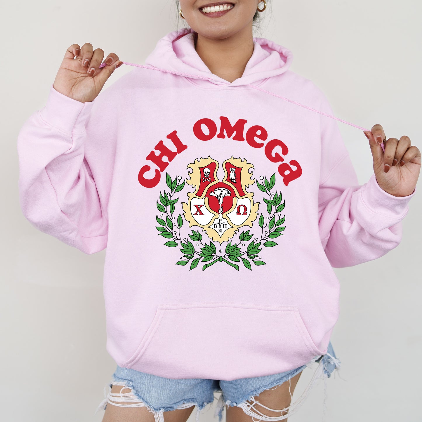 a woman wearing a pink hoodie with a crest on it