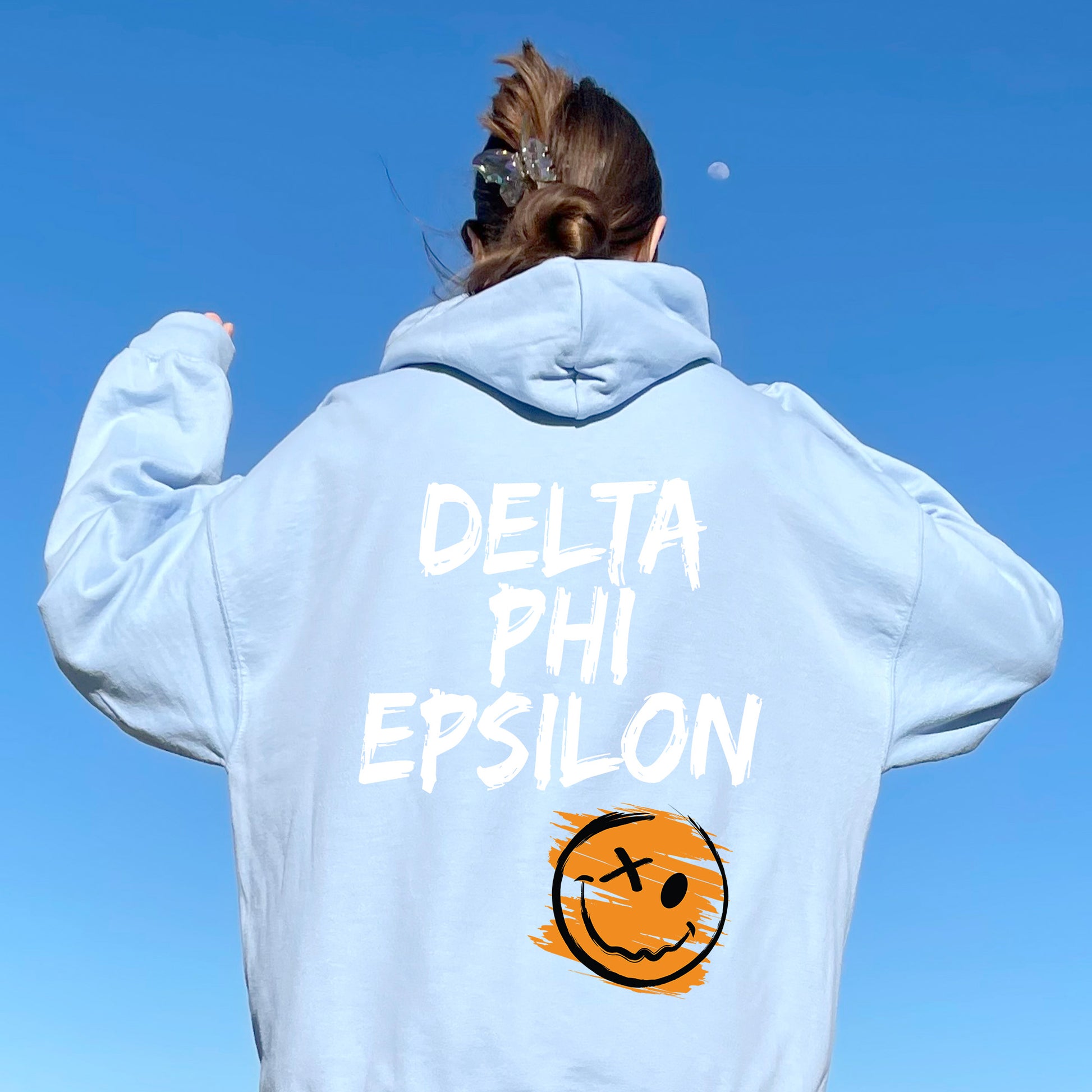 a woman wearing a sweatshirt that says delta phi epsilon