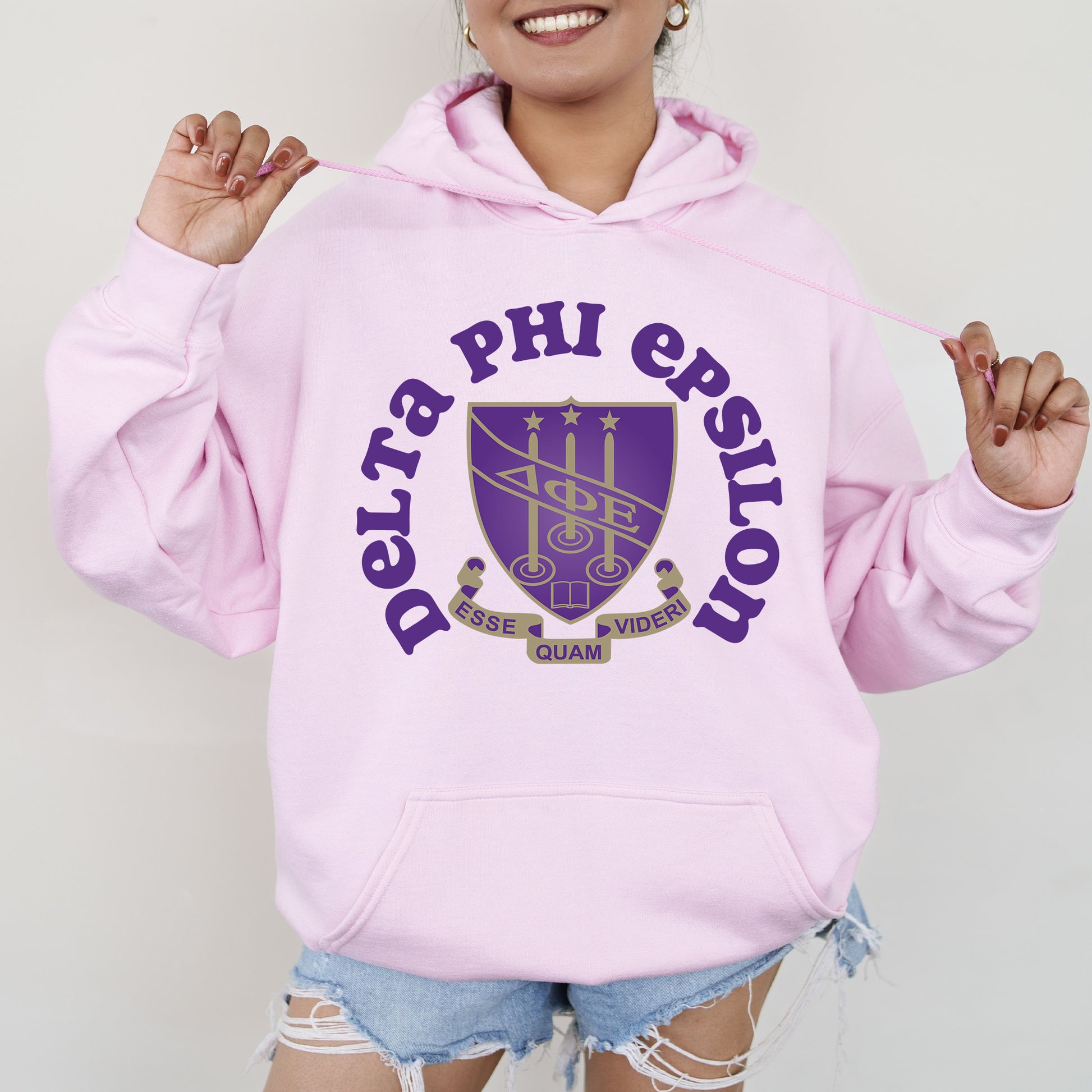 a woman wearing a pink hoodie with purple letters on it