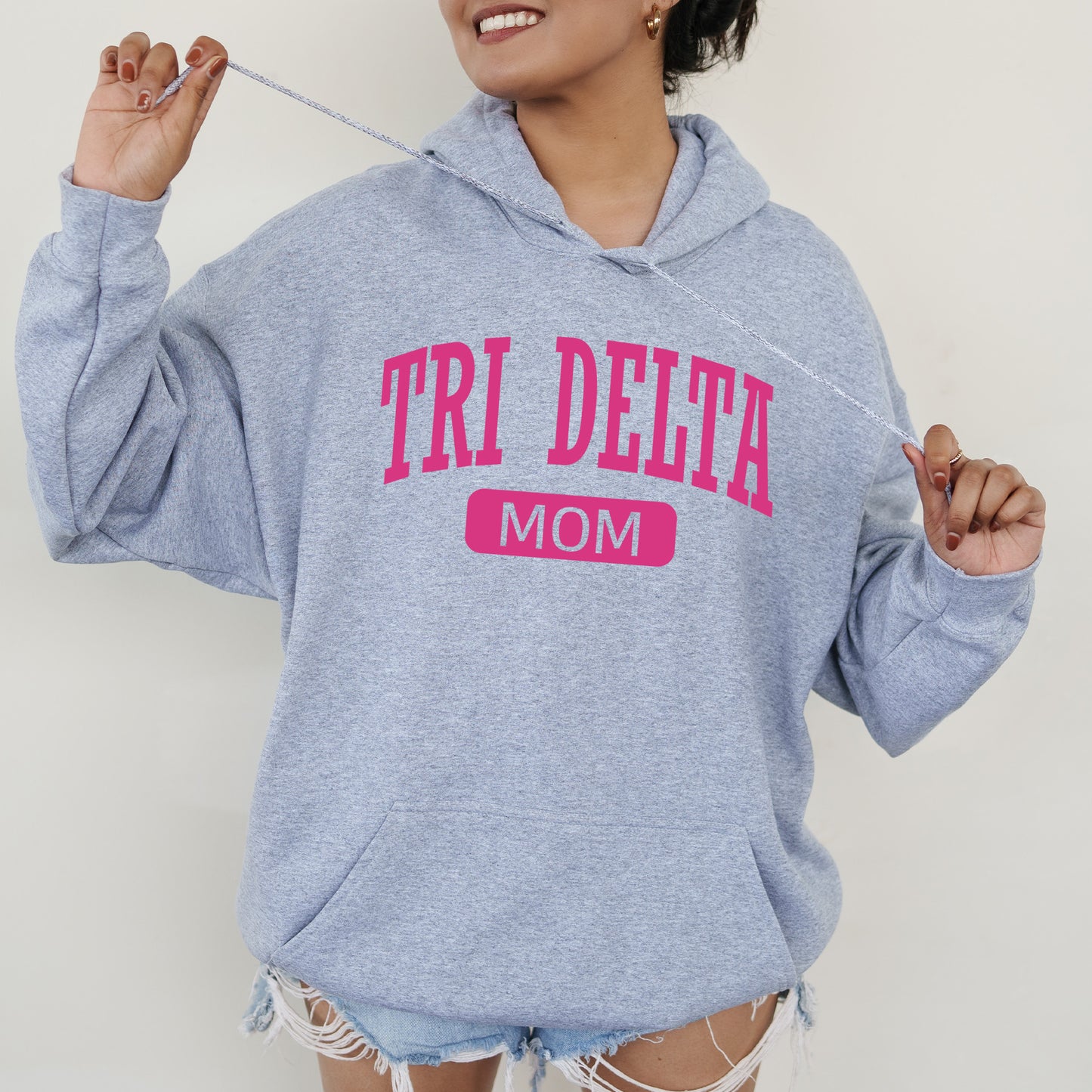 a woman wearing a sweatshirt that says tri delta mom