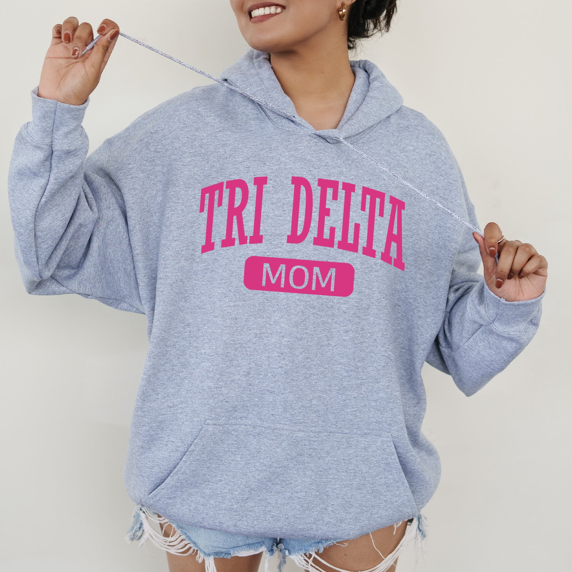 a woman wearing a sweatshirt that says tri delta mom