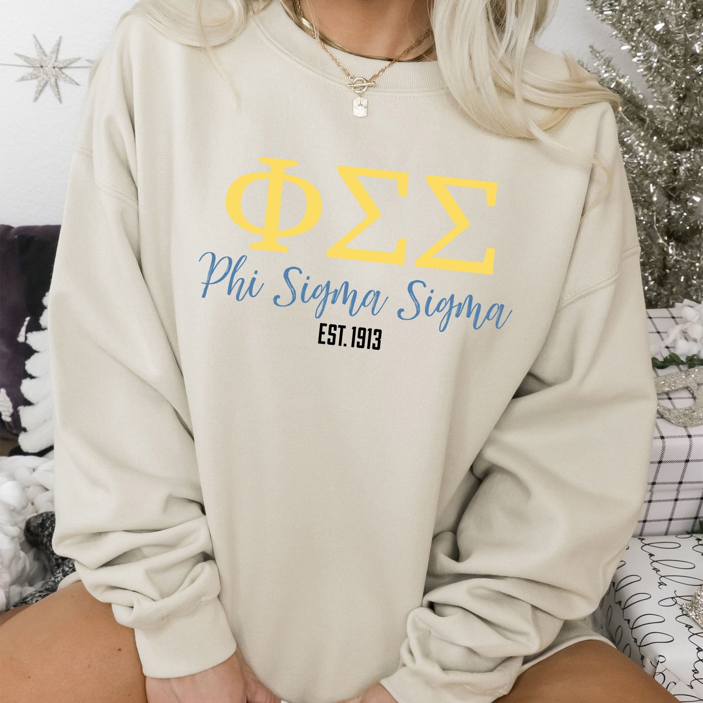 a woman sitting on a bed wearing a sweatshirt