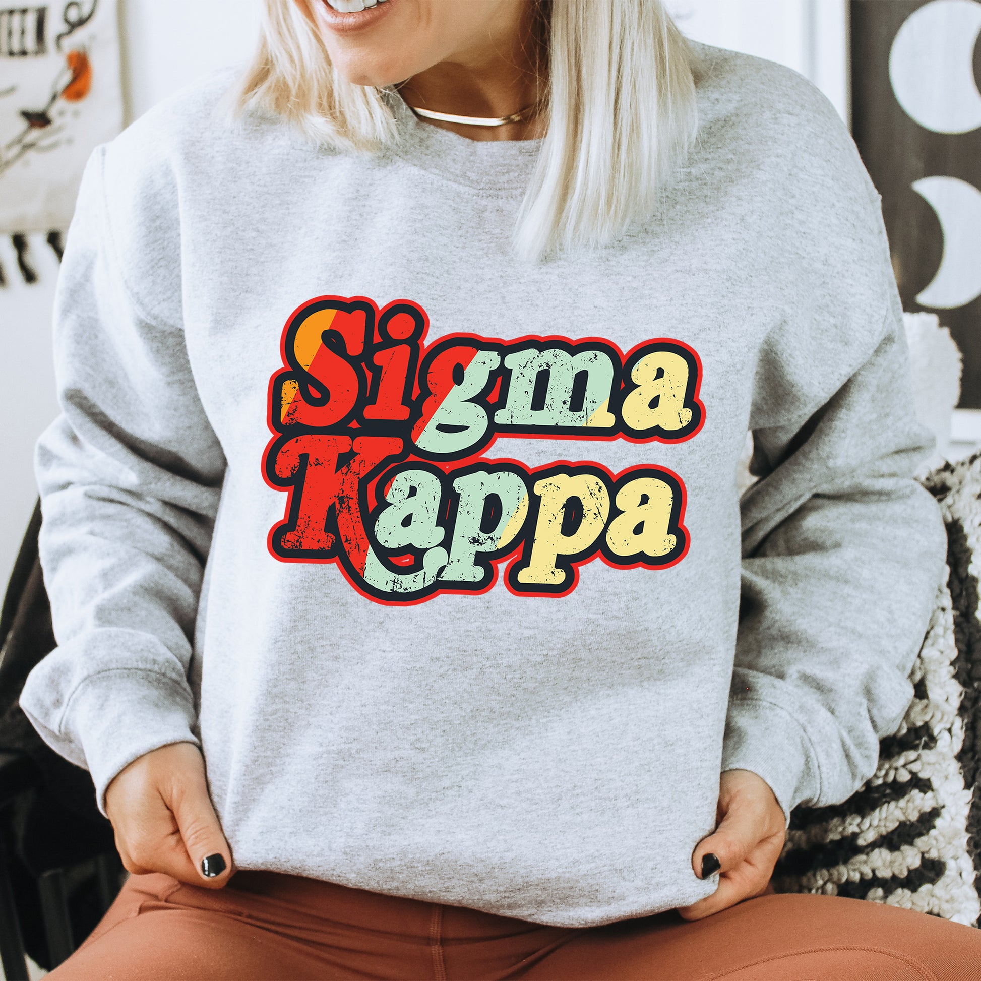 a woman sitting on a chair wearing a sweatshirt with the word stigma kappa