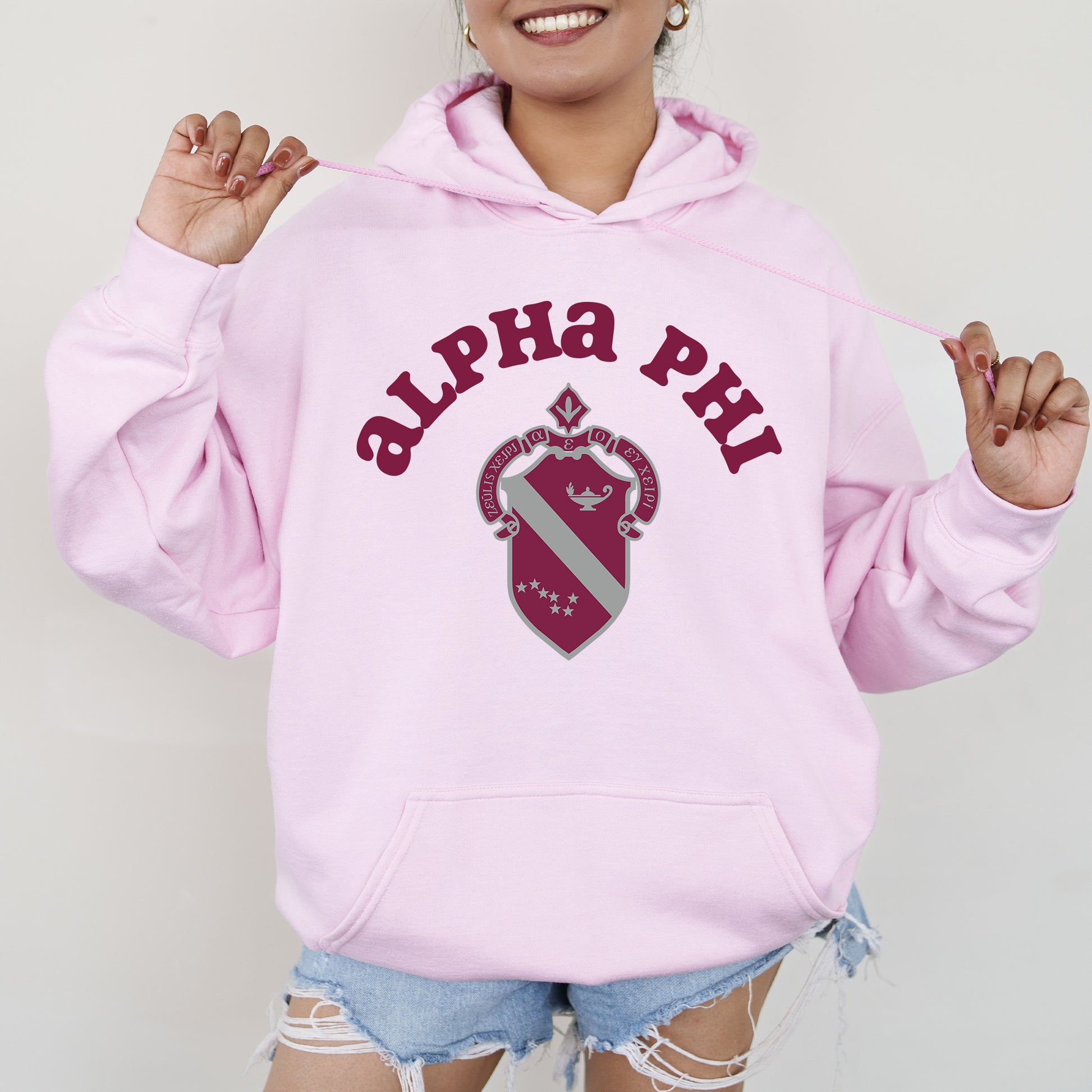 a woman wearing a pink hoodie with the words alpha phi on it