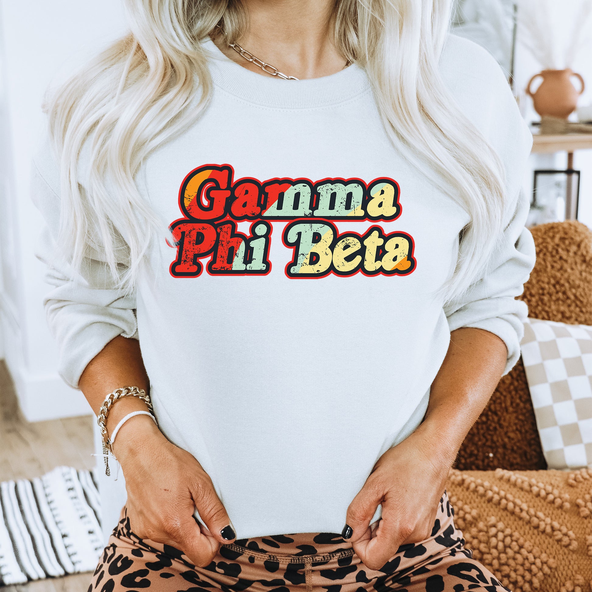 a woman wearing a white sweatshirt with the words gama phi beta on it