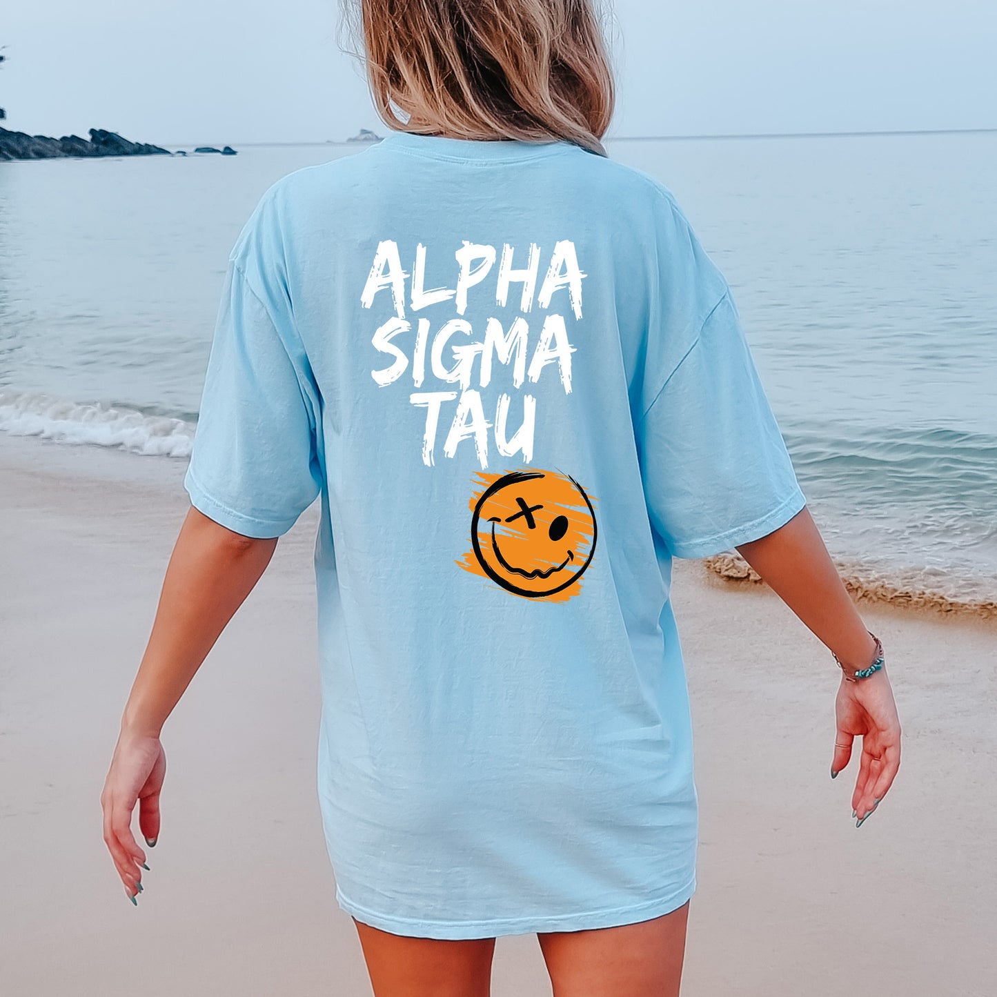 a woman walking on the beach with a smiley face on her shirt