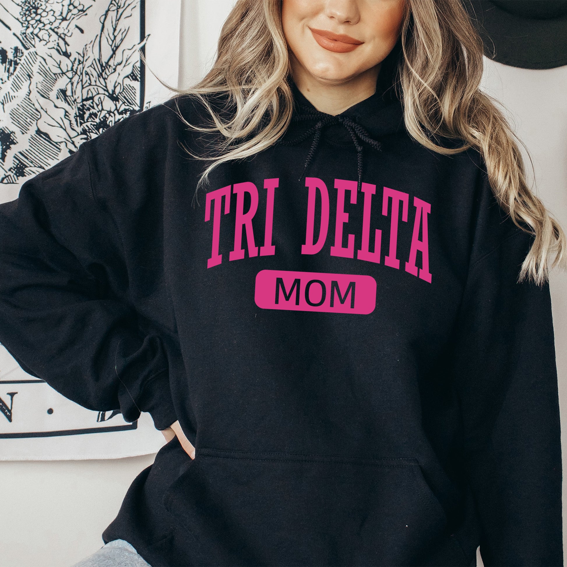 a woman wearing a black hoodie that says tri delta mom