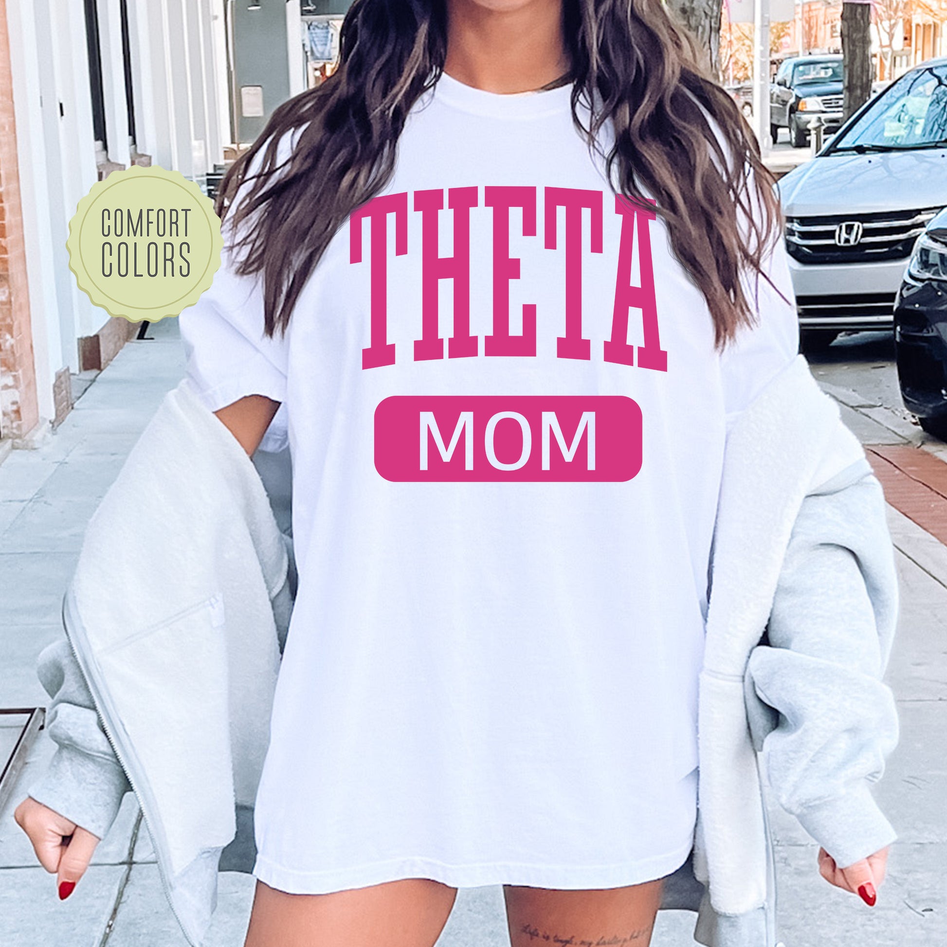 a woman wearing a white shirt with the words'theta mom'on it