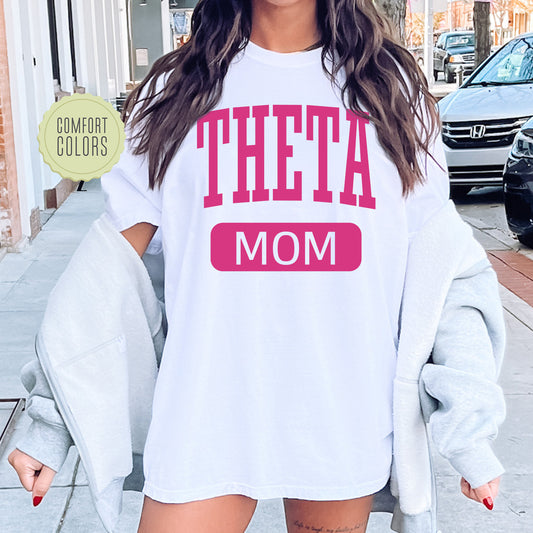 a woman wearing a white shirt with the words'theta mom'on it