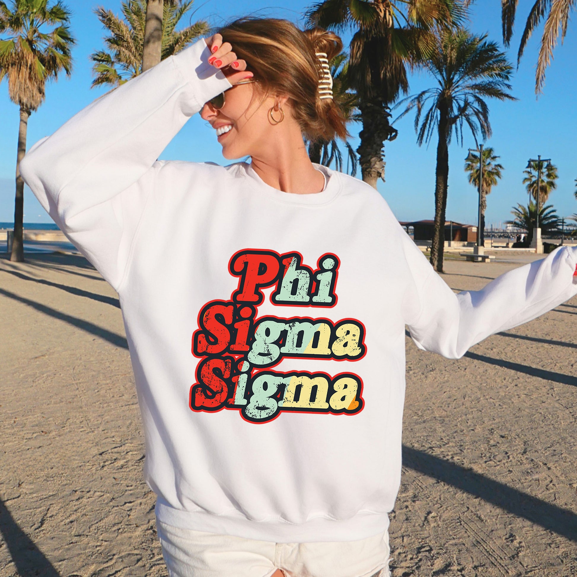 a woman standing on a beach wearing a white sweatshirt