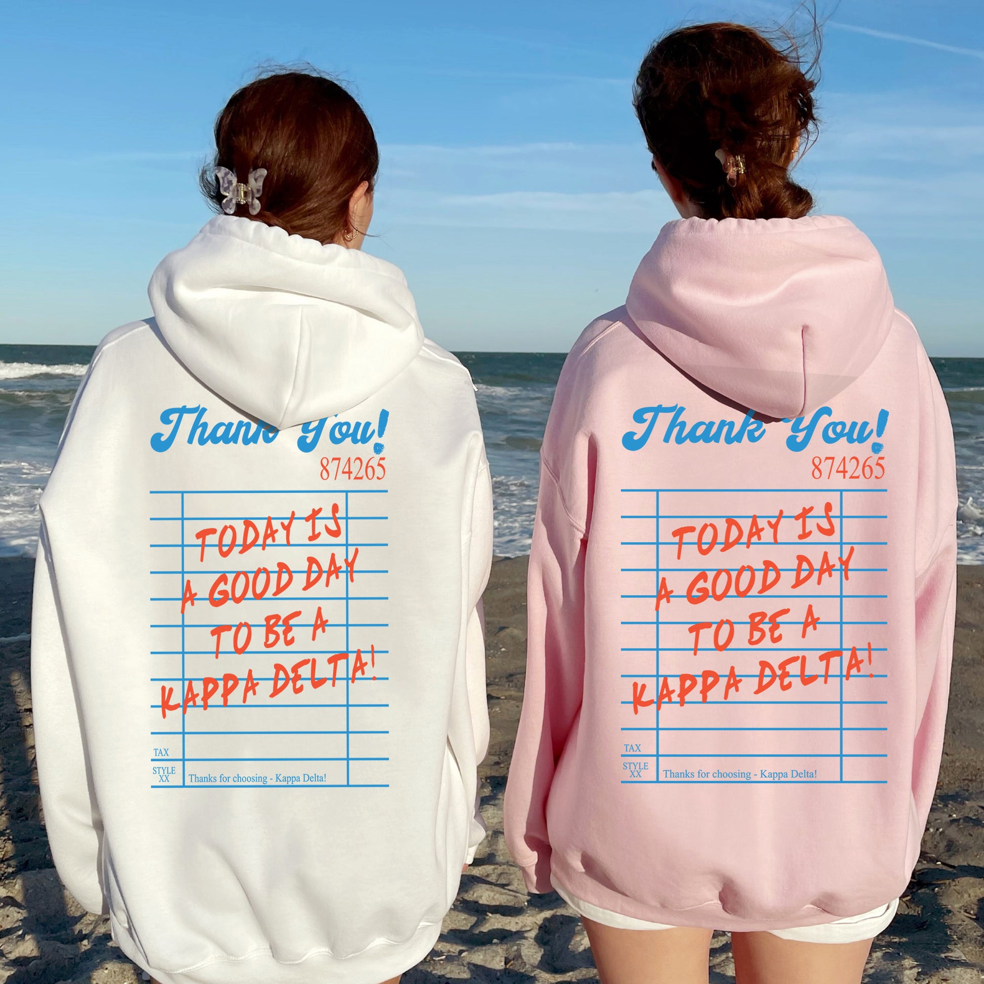 two people standing on a beach wearing matching sweatshirts