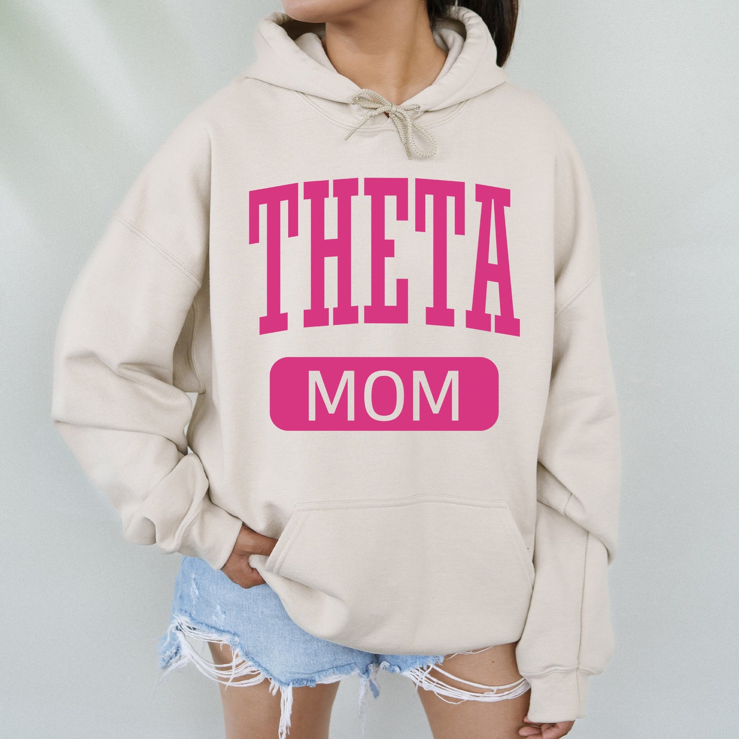 a woman wearing a sweatshirt that says theta mom