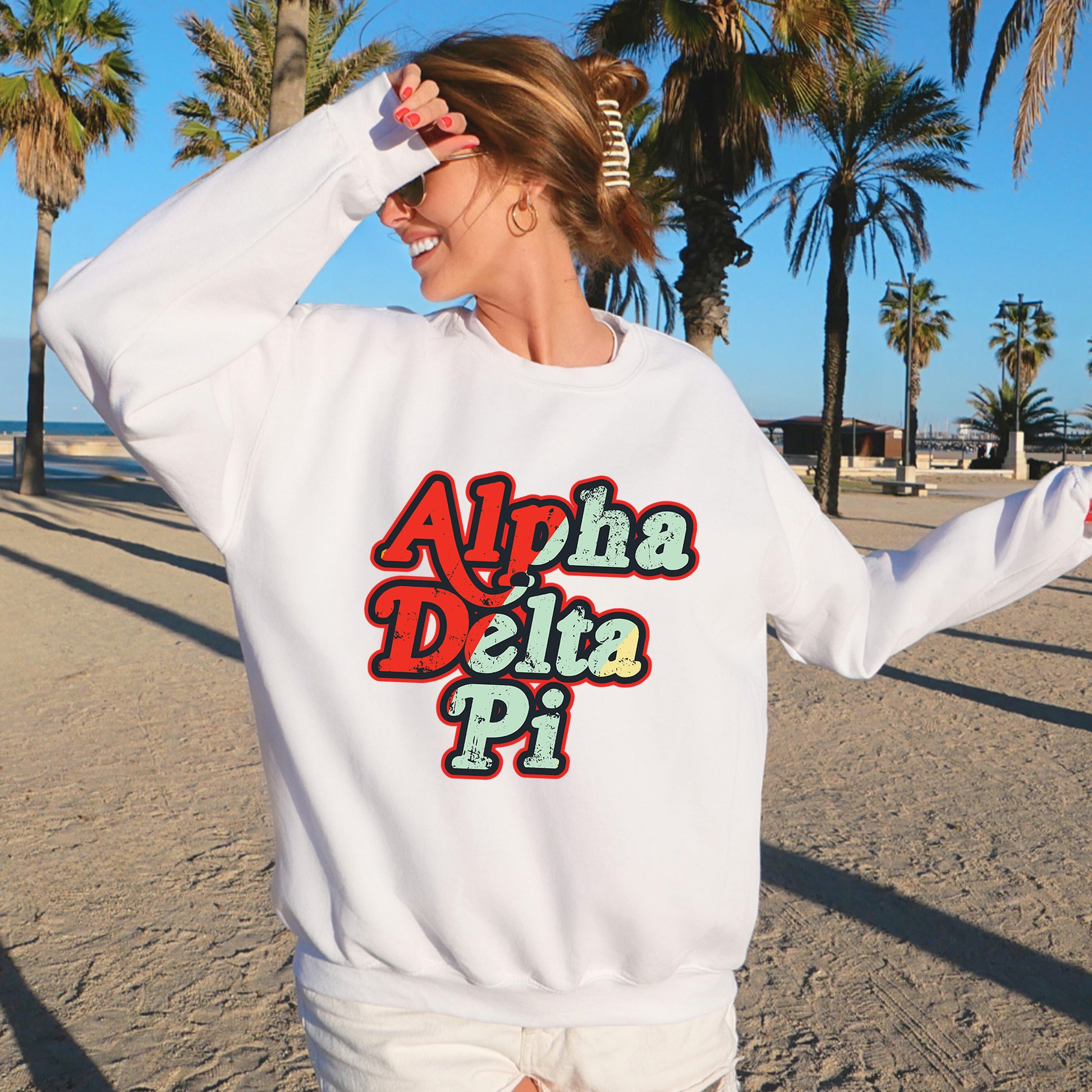 a woman standing on a beach wearing a white sweatshirt