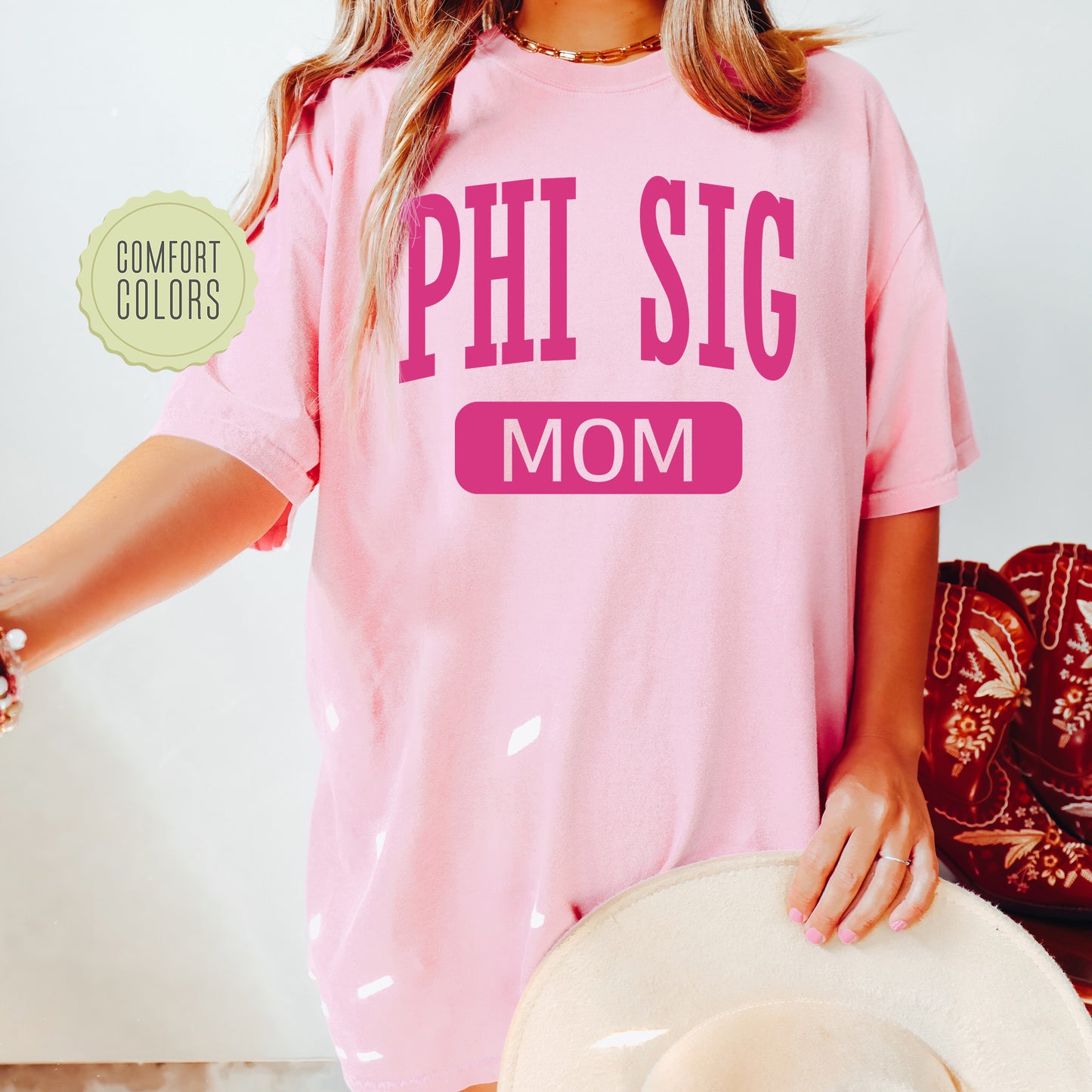 a woman wearing a pink shirt that says phi sig mom
