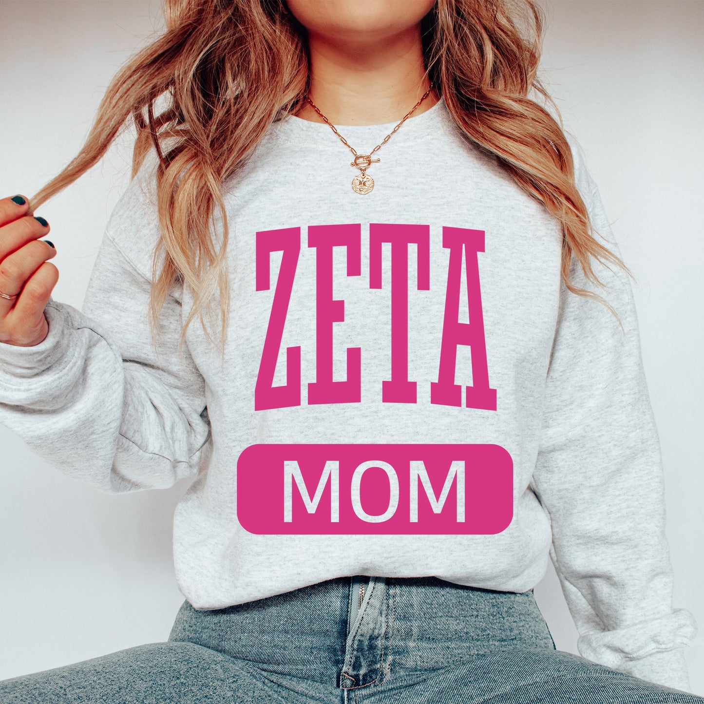 a woman wearing a sweatshirt that says zeta mom