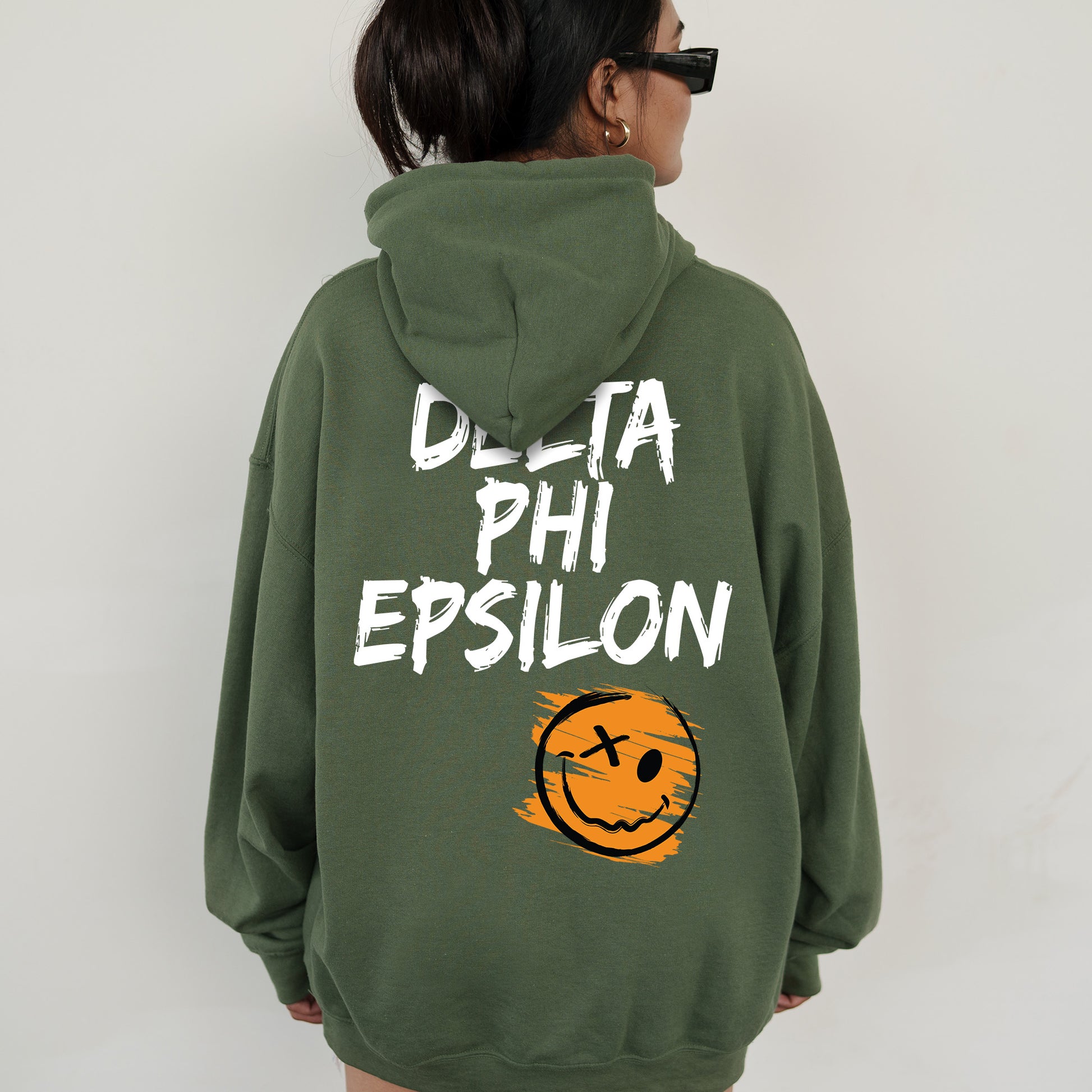 a woman wearing a green sweatshirt with the words delta phi epsilon printed on