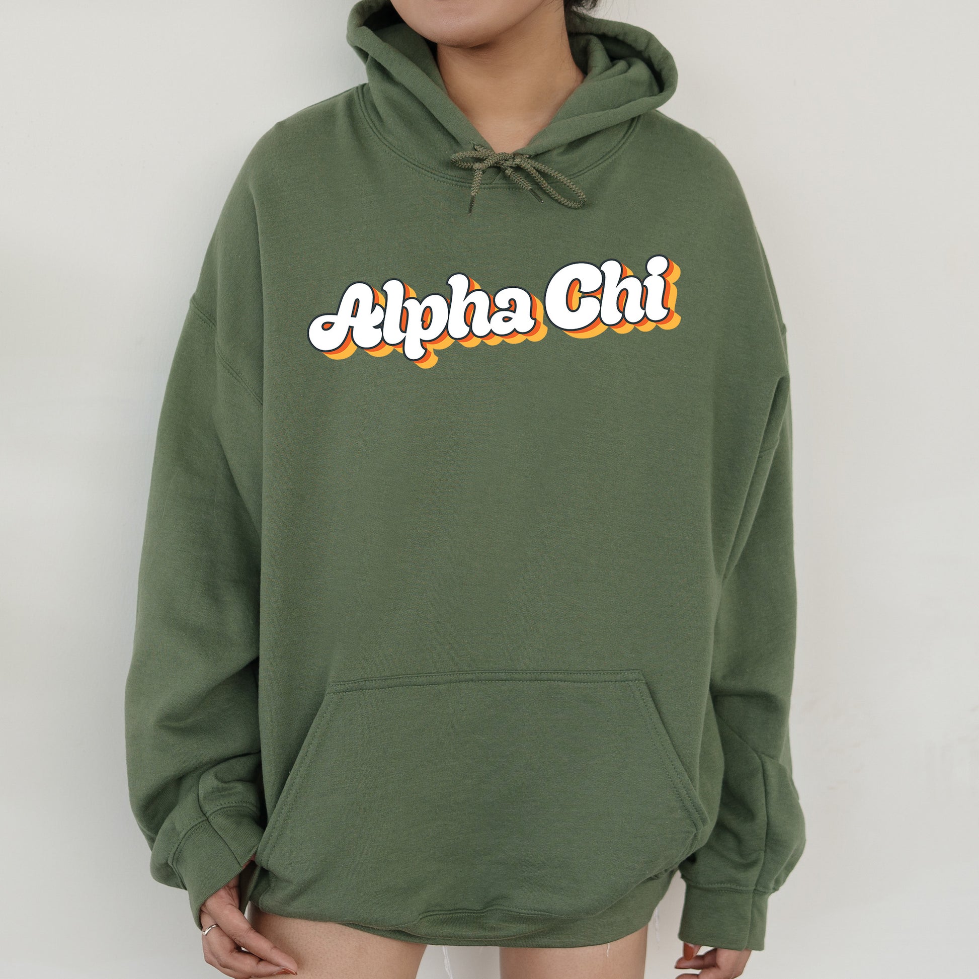a person wearing a green hoodie with the word alpha chi on it