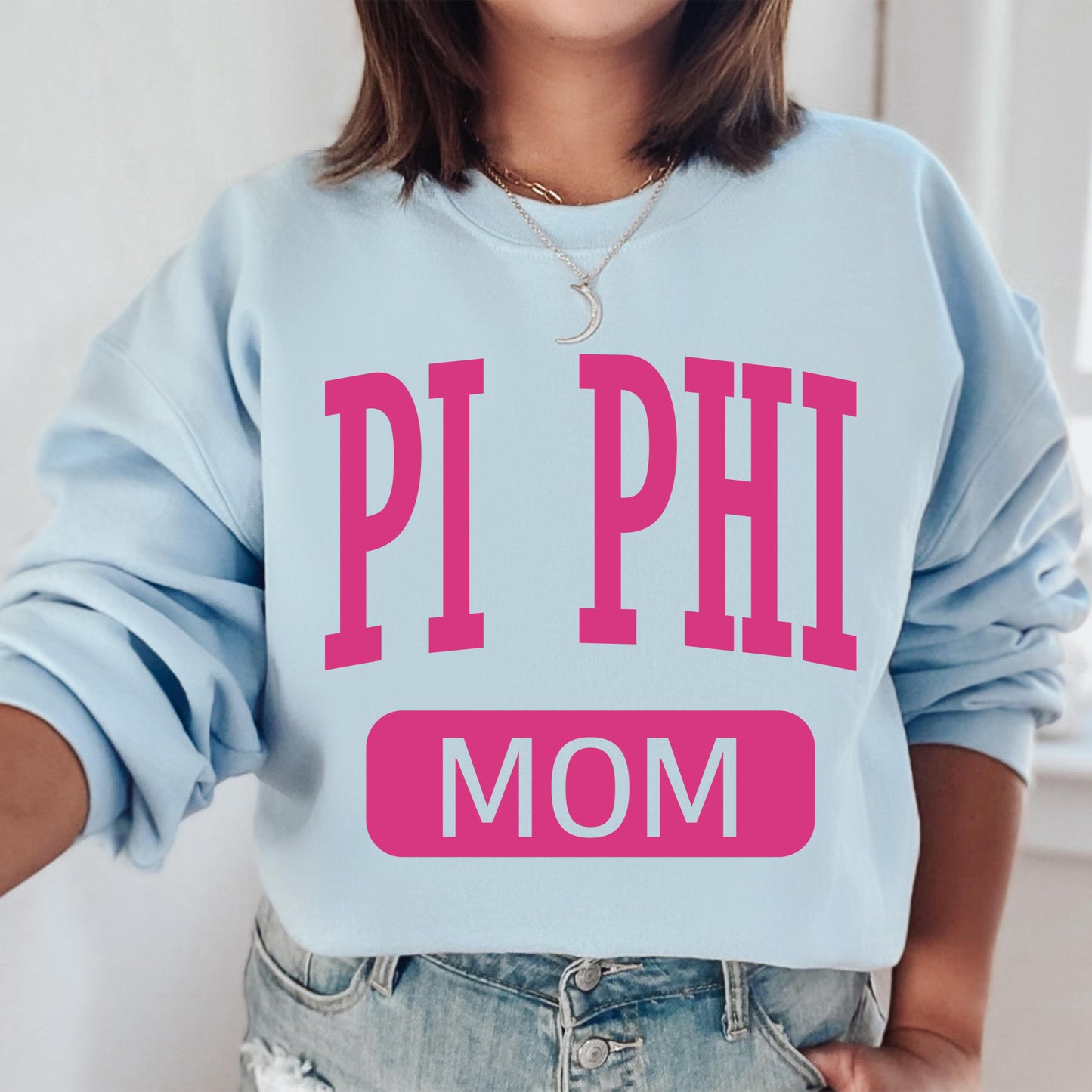 a woman wearing a sweatshirt that says pi phi mom