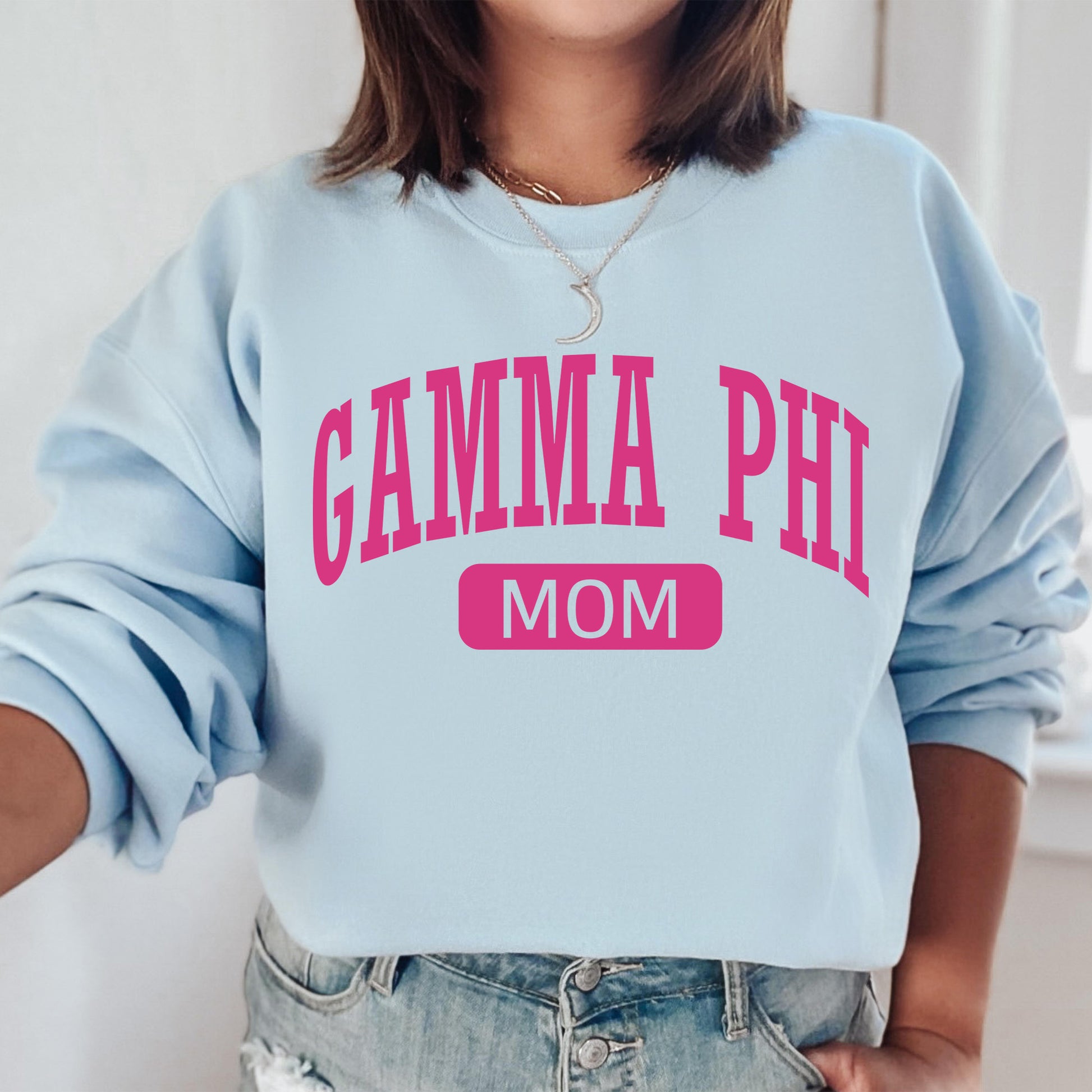 a woman wearing a light blue sweatshirt with pink lettering