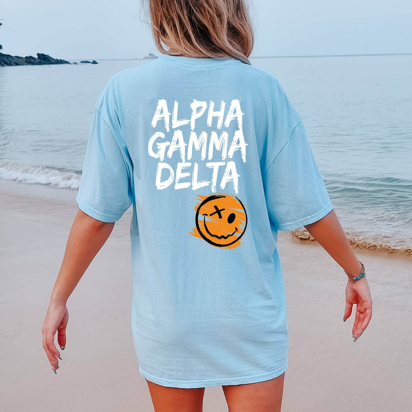 a woman walking on the beach with a smile on her shirt