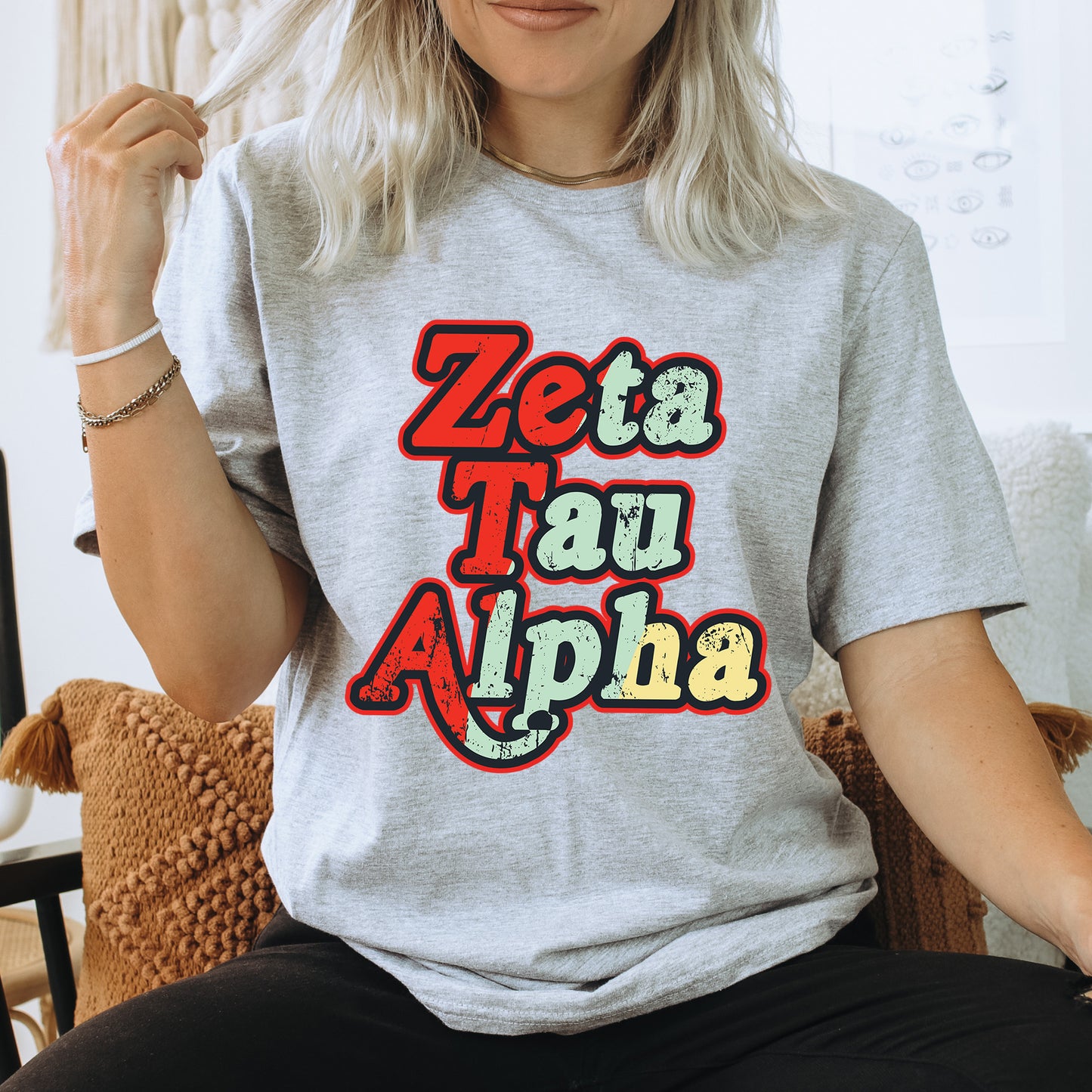 a woman sitting on a chair wearing a t - shirt that says zeta tau