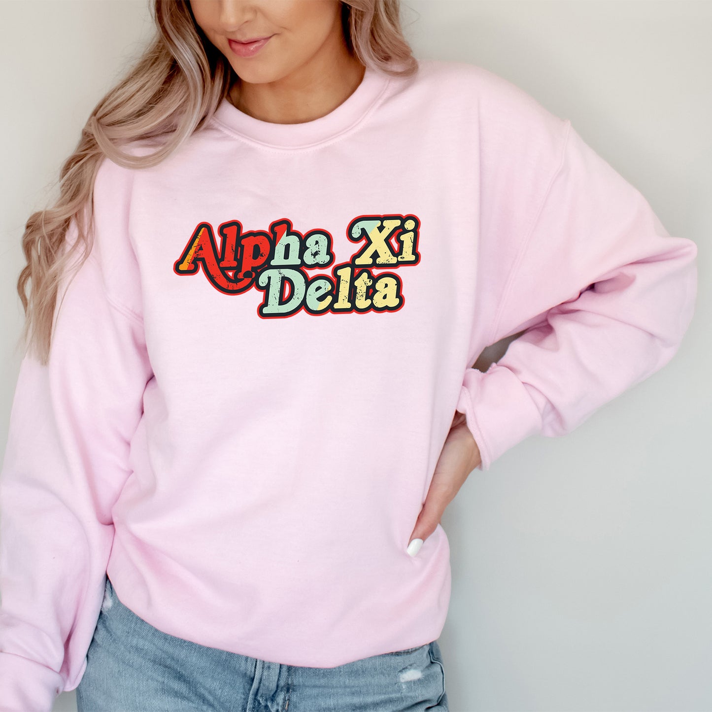 a woman wearing a pink sweatshirt that says alpha xi delta