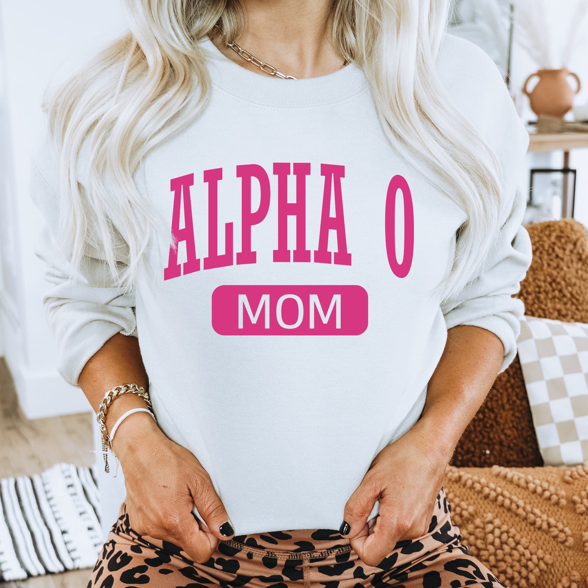 a woman with blonde hair wearing a white sweatshirt with pink letters