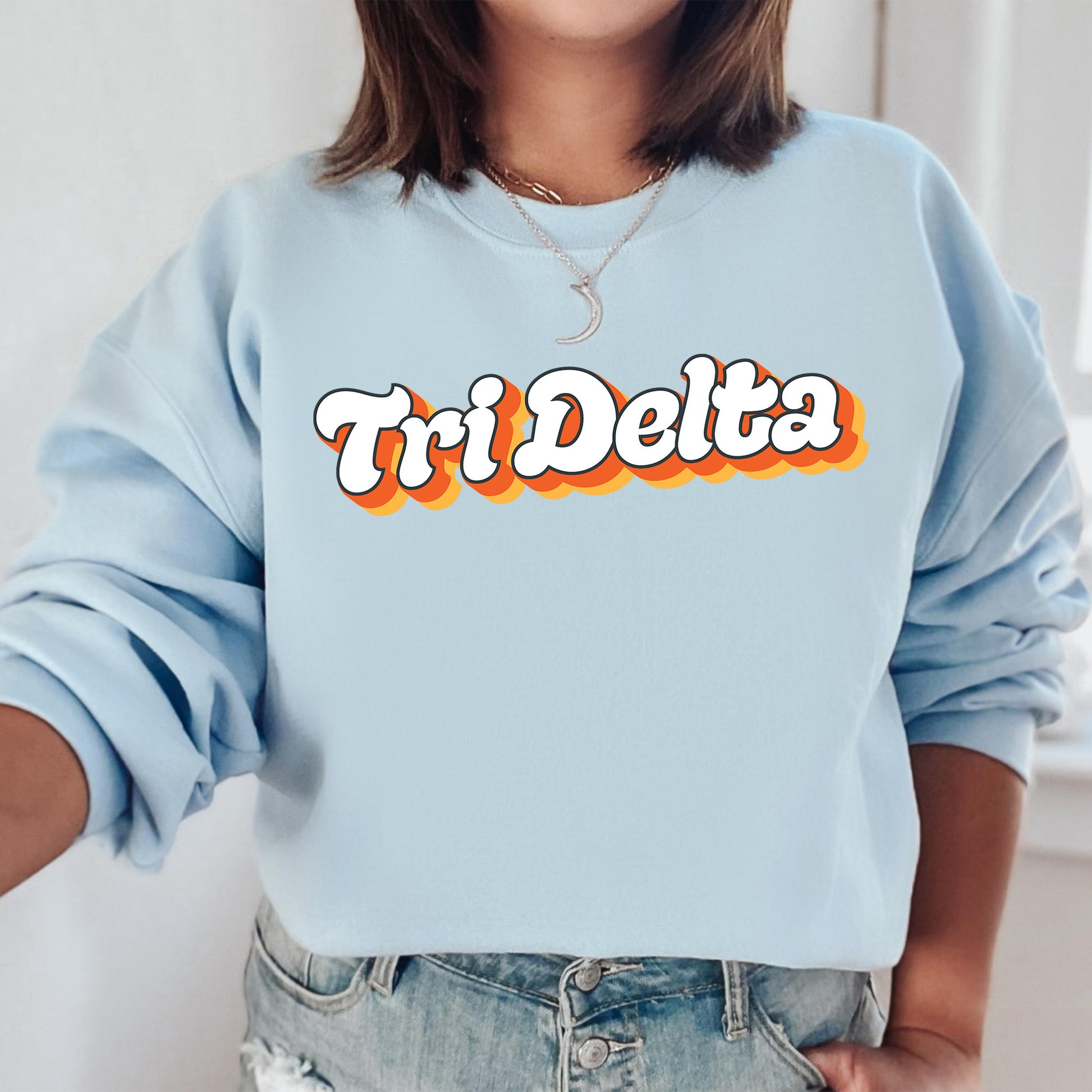 a woman wearing a blue sweatshirt with the word tri delta printed on it