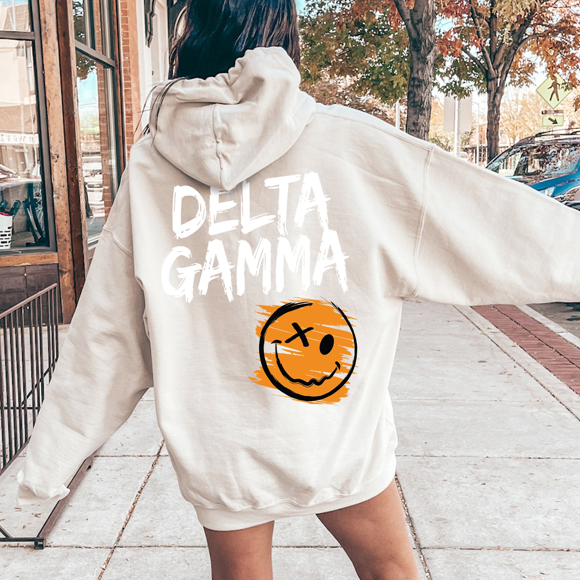 a woman wearing a white sweatshirt with a smiley face drawn on it