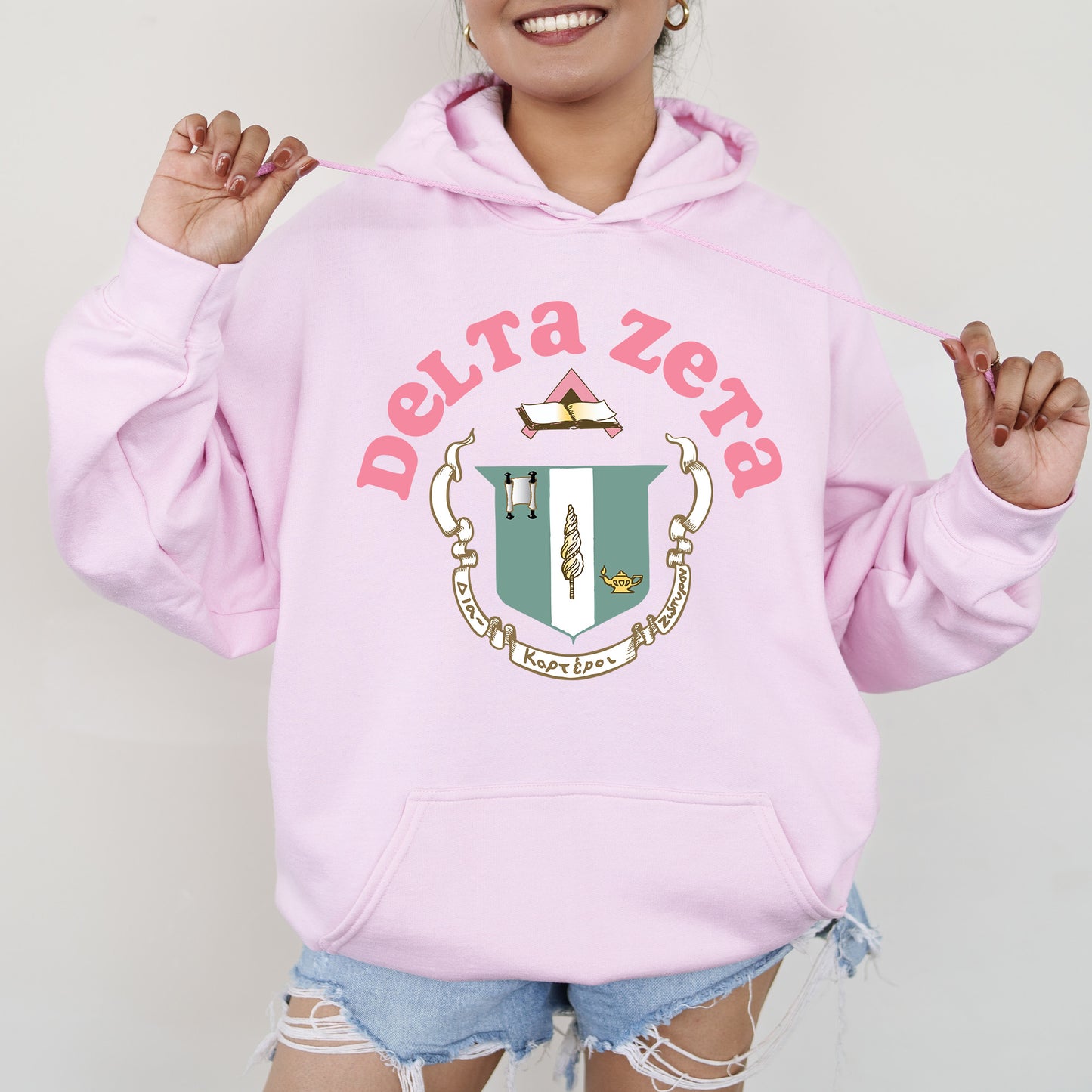 a woman wearing a pink sweatshirt with a crest on it
