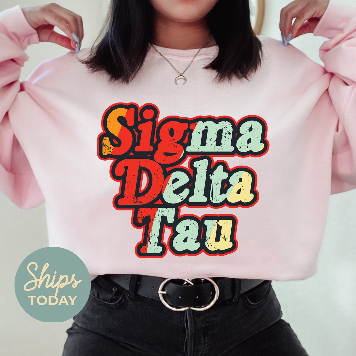 a woman wearing a pink sweatshirt with the words sigma delta tau on it