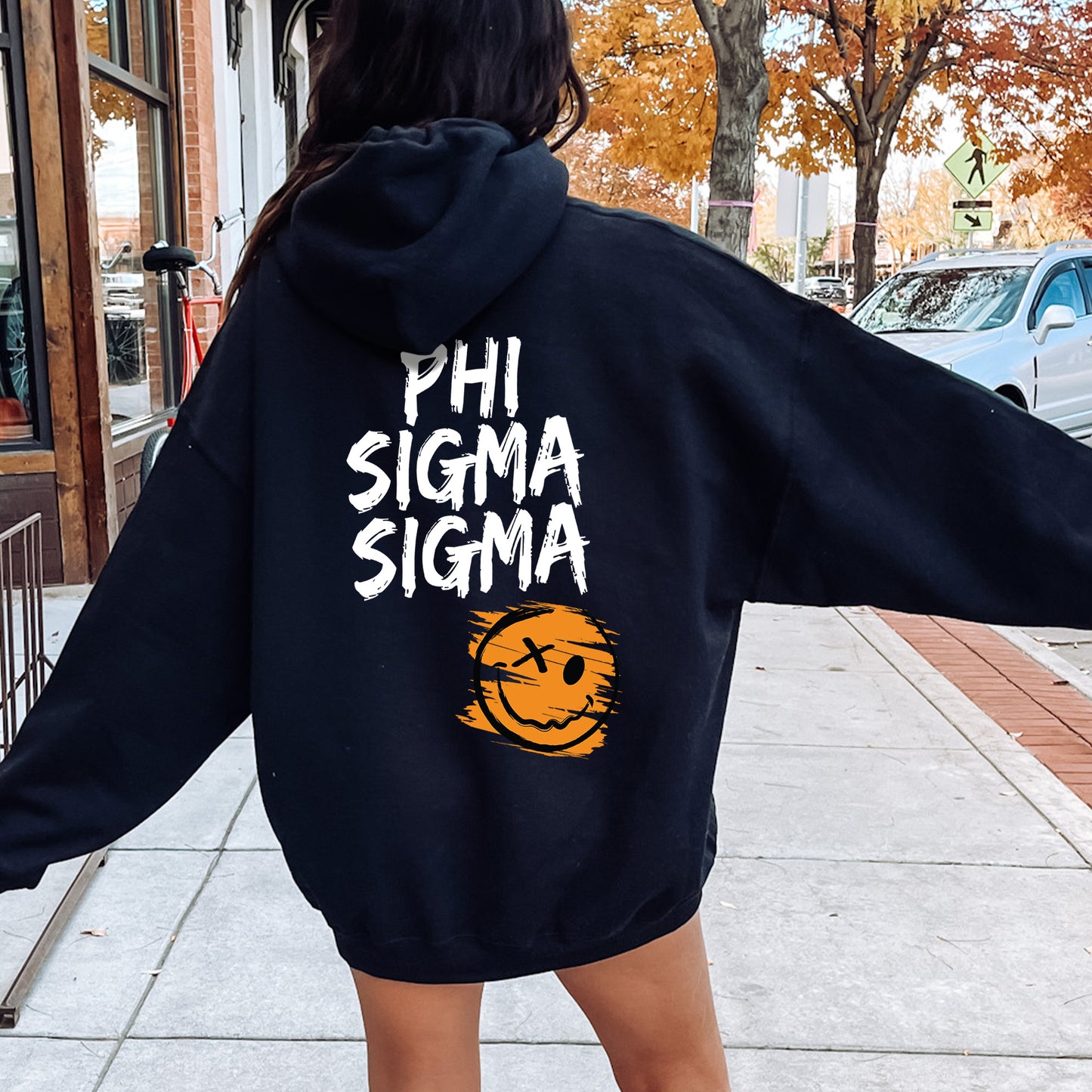 a woman walking down a sidewalk wearing a black sweatshirt