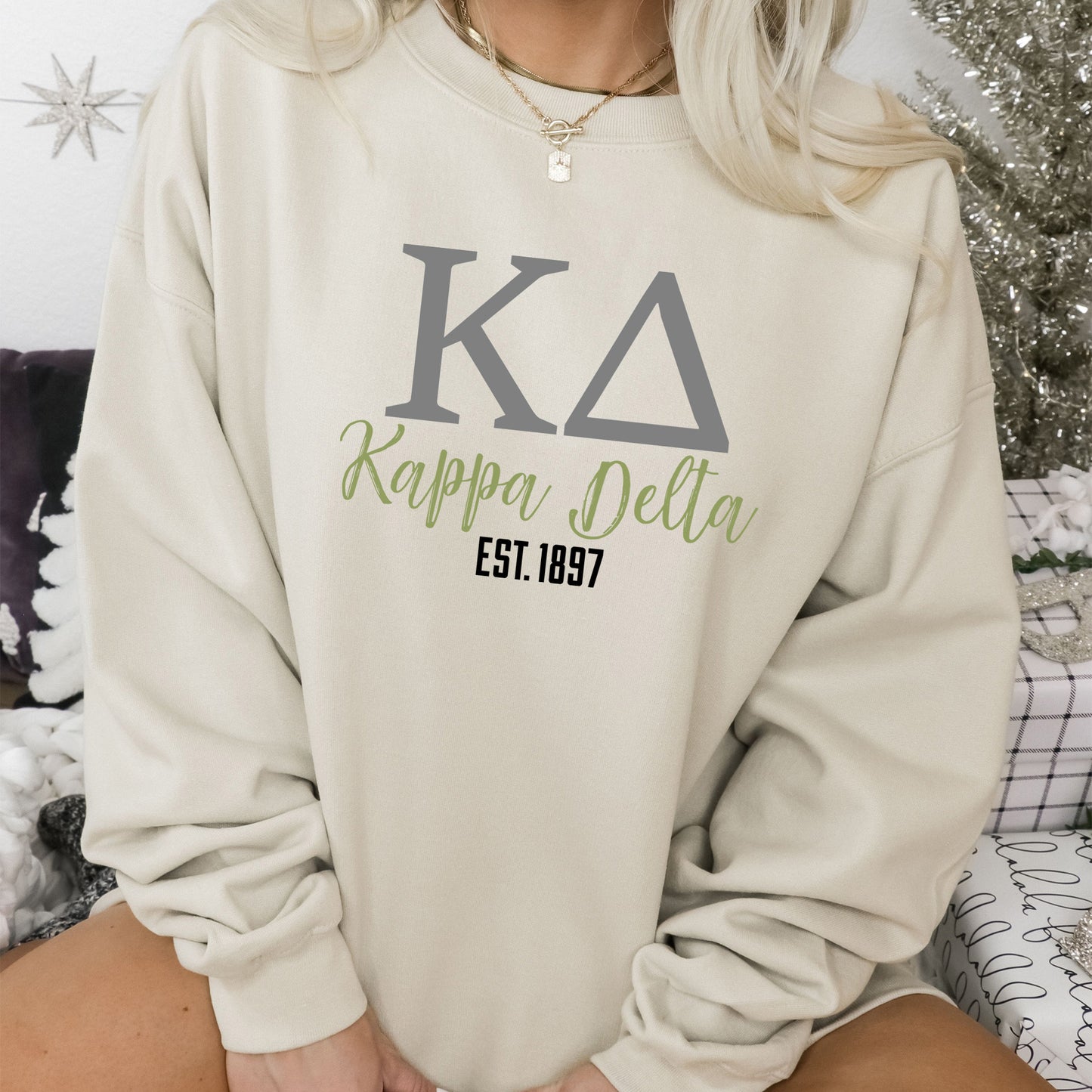 a woman sitting on a bed wearing a sweatshirt