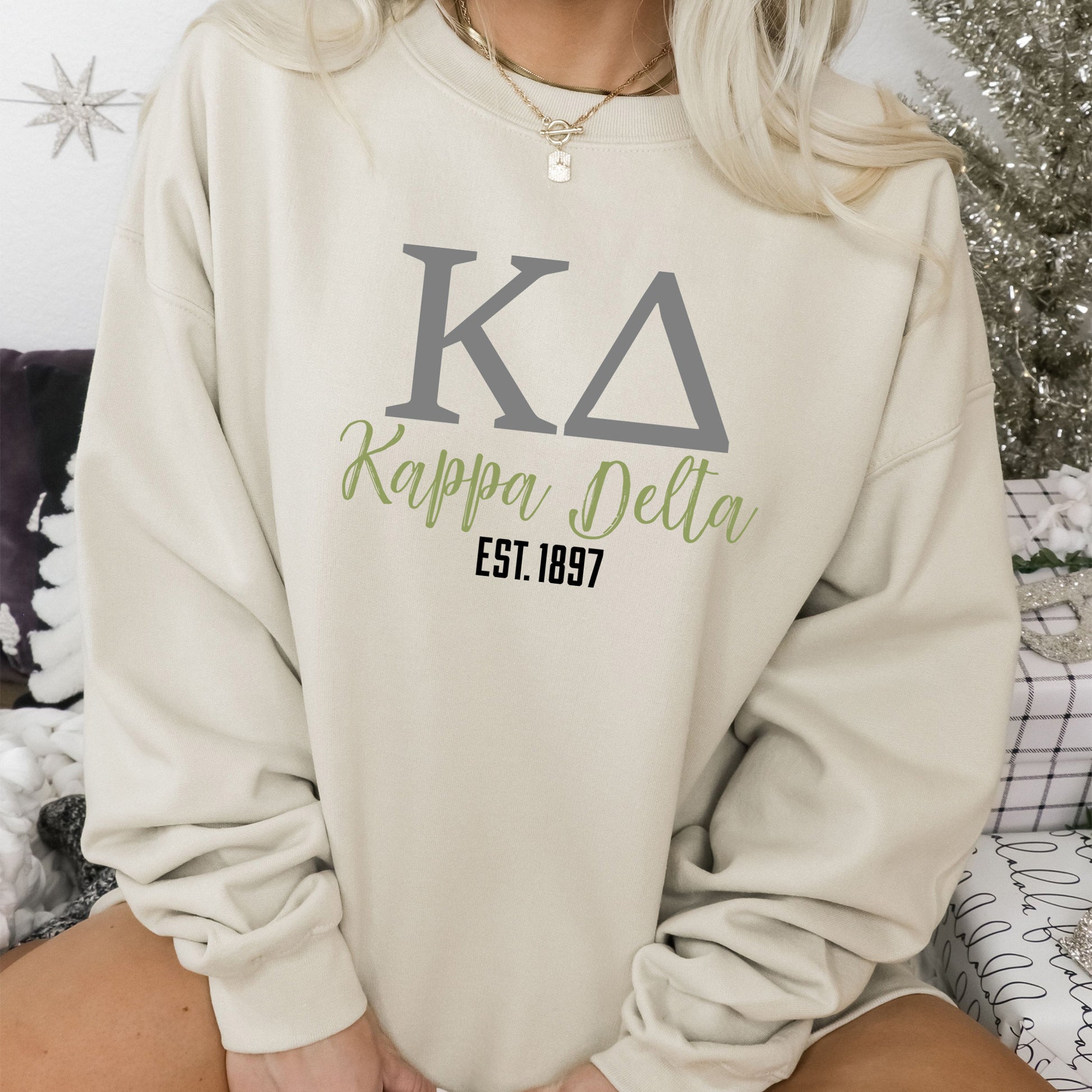 a woman sitting on a bed wearing a sweatshirt