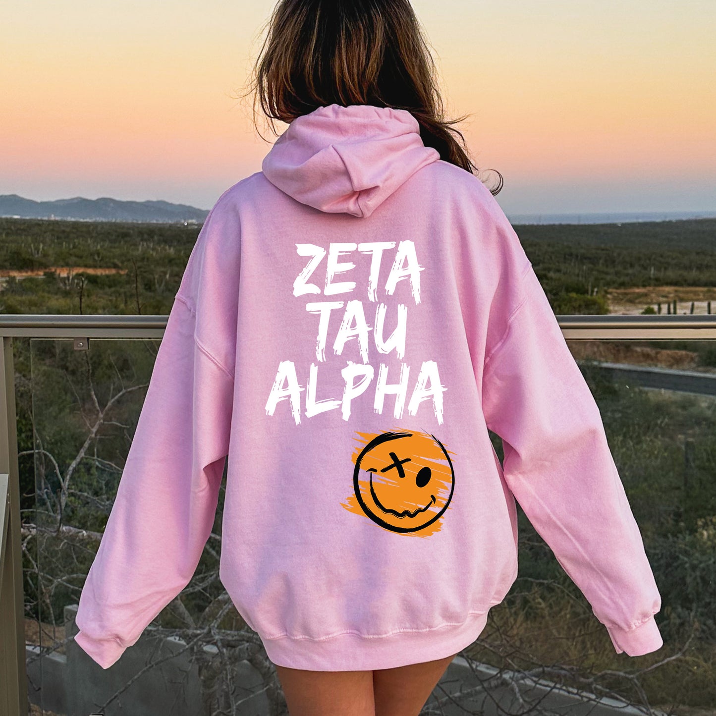 a girl in a pink hoodie that says zeta tau alpha