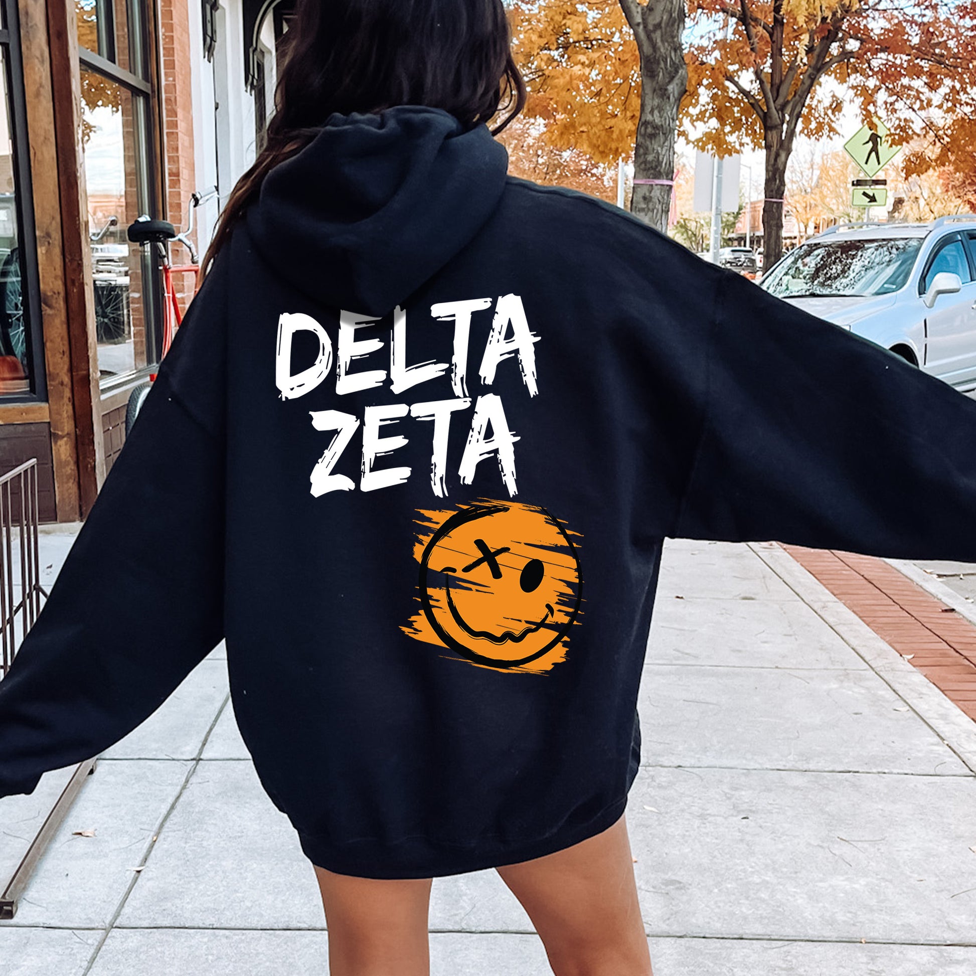 a woman walking down a sidewalk wearing a black sweatshirt
