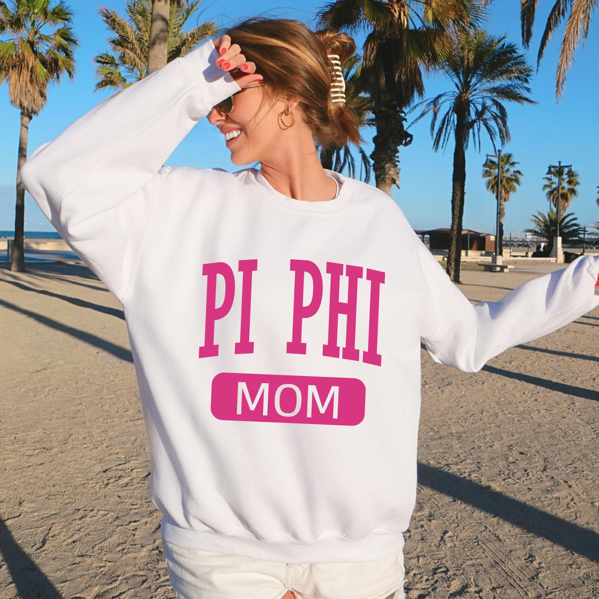 a woman wearing a sweatshirt that says pi phi mom