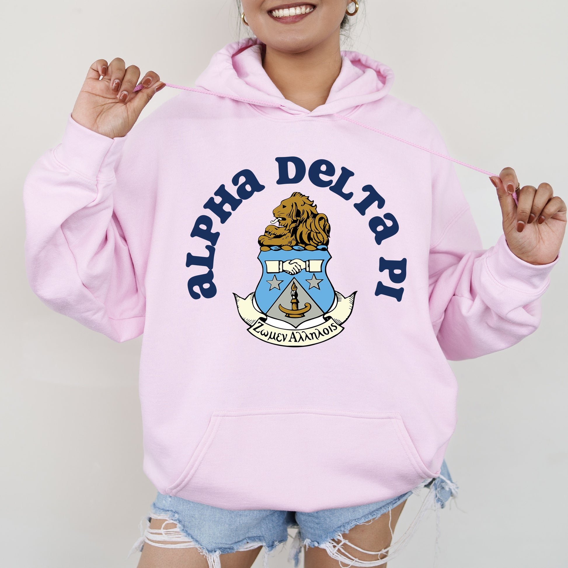 a woman wearing a pink sweatshirt and ripped shorts