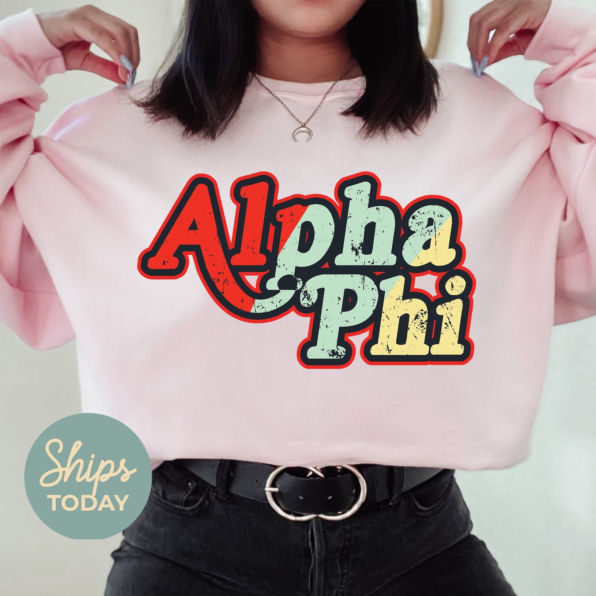 a woman wearing a pink sweatshirt with the word alpha phi on it