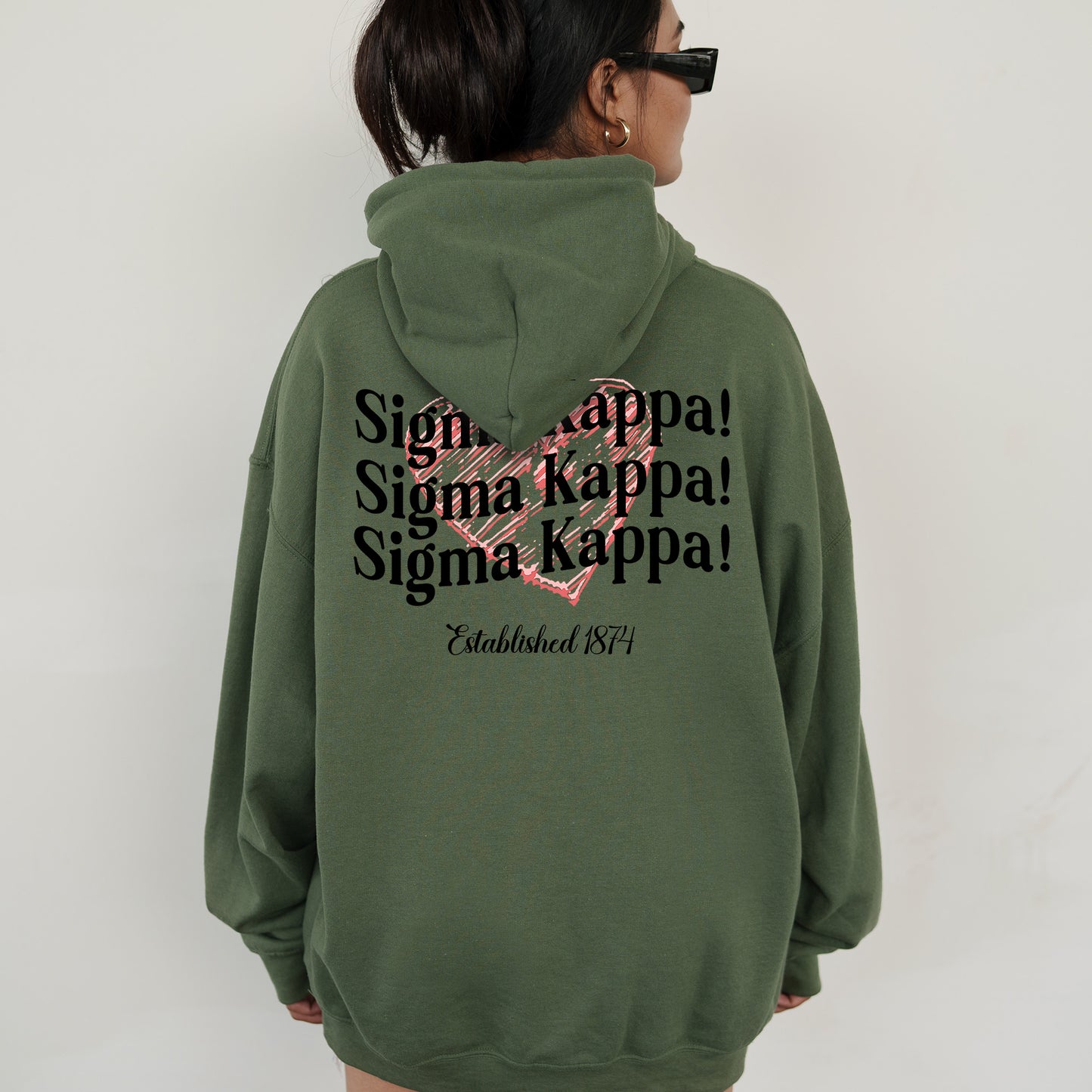 a woman wearing a green hoodie with a pink heart on it