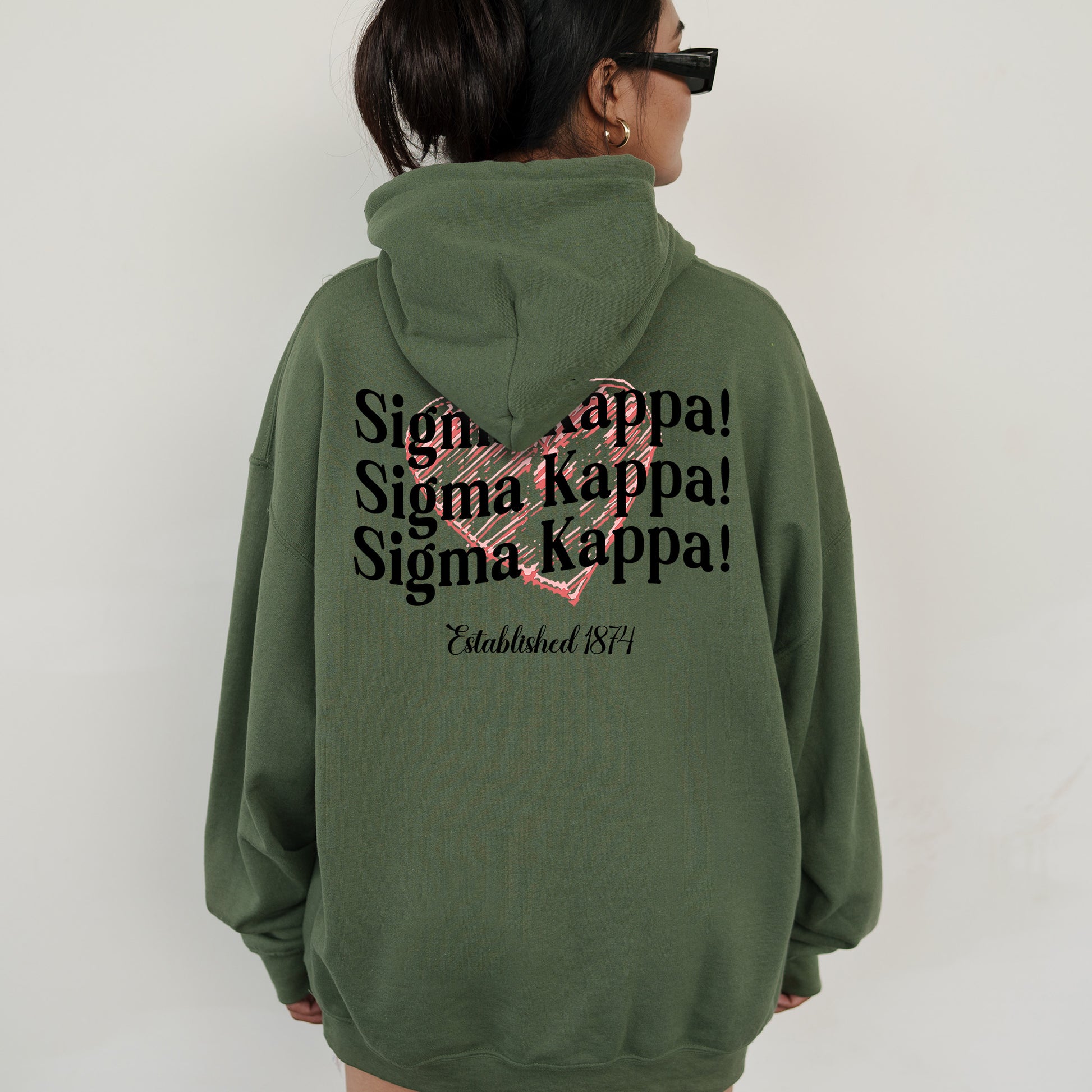 a woman wearing a green hoodie with a pink heart on it