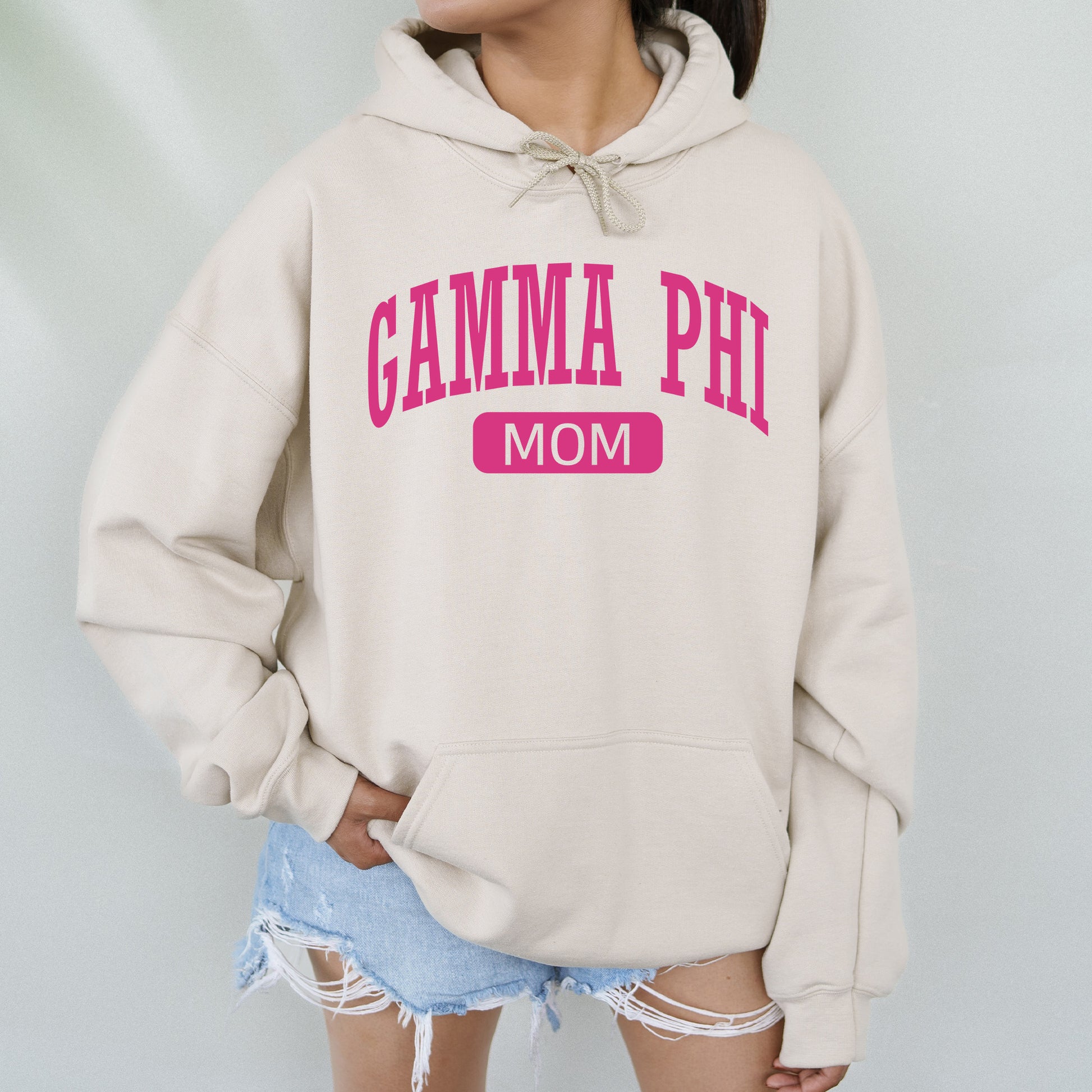 a woman wearing a sweatshirt that says gamma phi mom