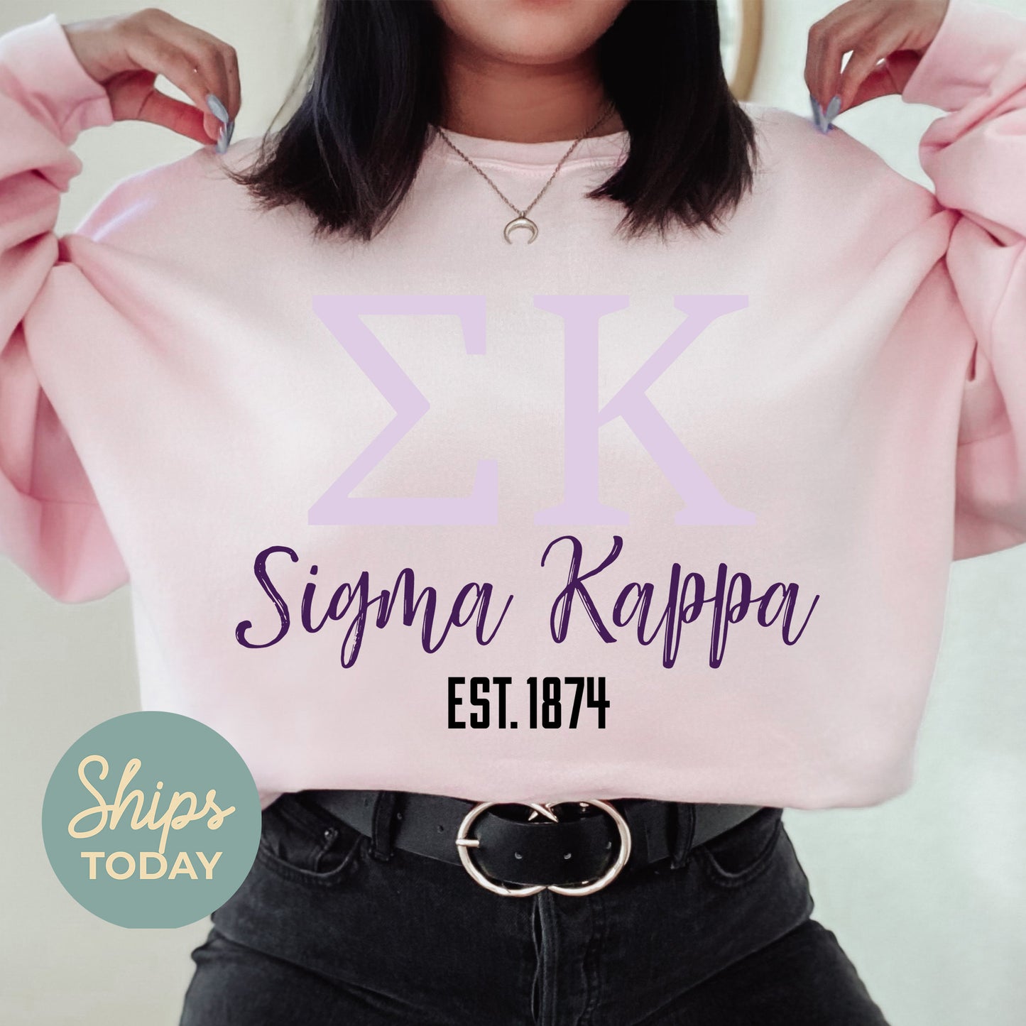 a woman holding a pink sweater with a cross on it