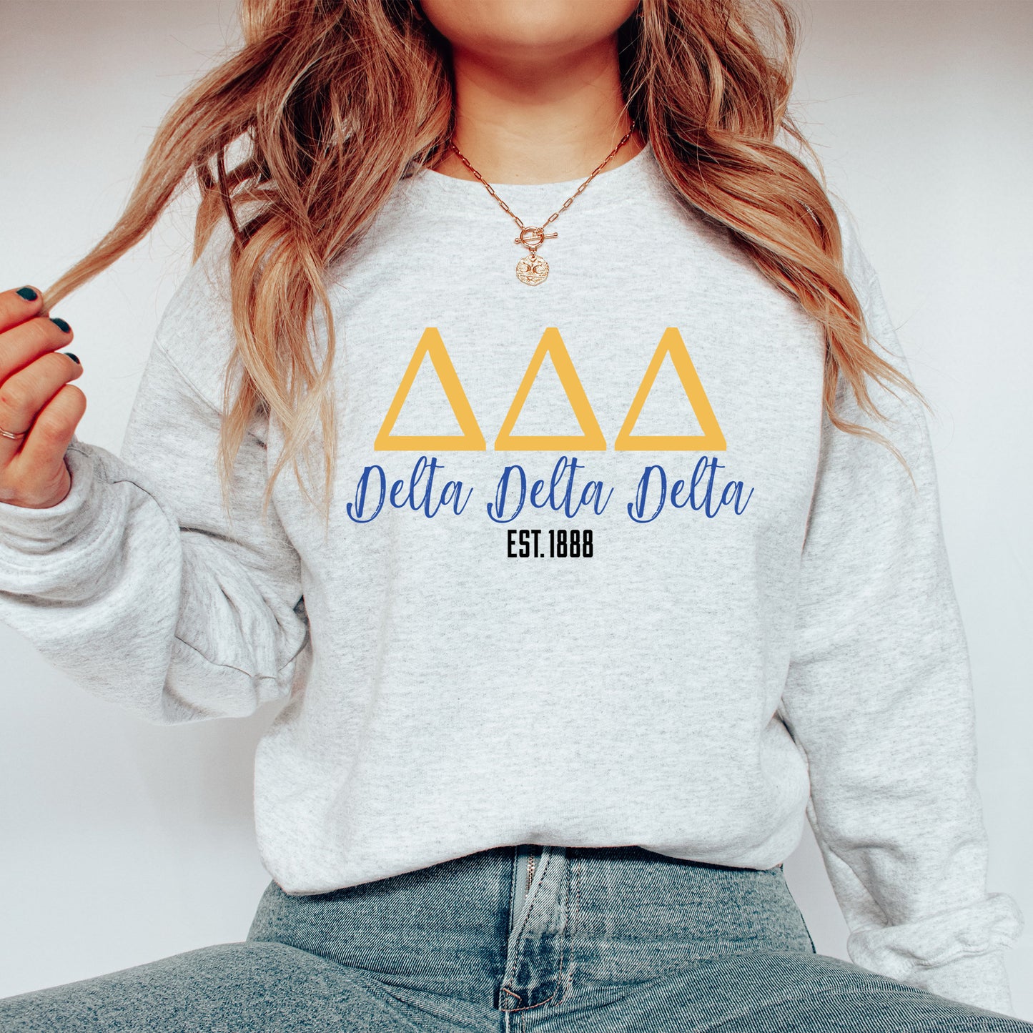 a woman wearing a delta delta sweatshirt and jeans